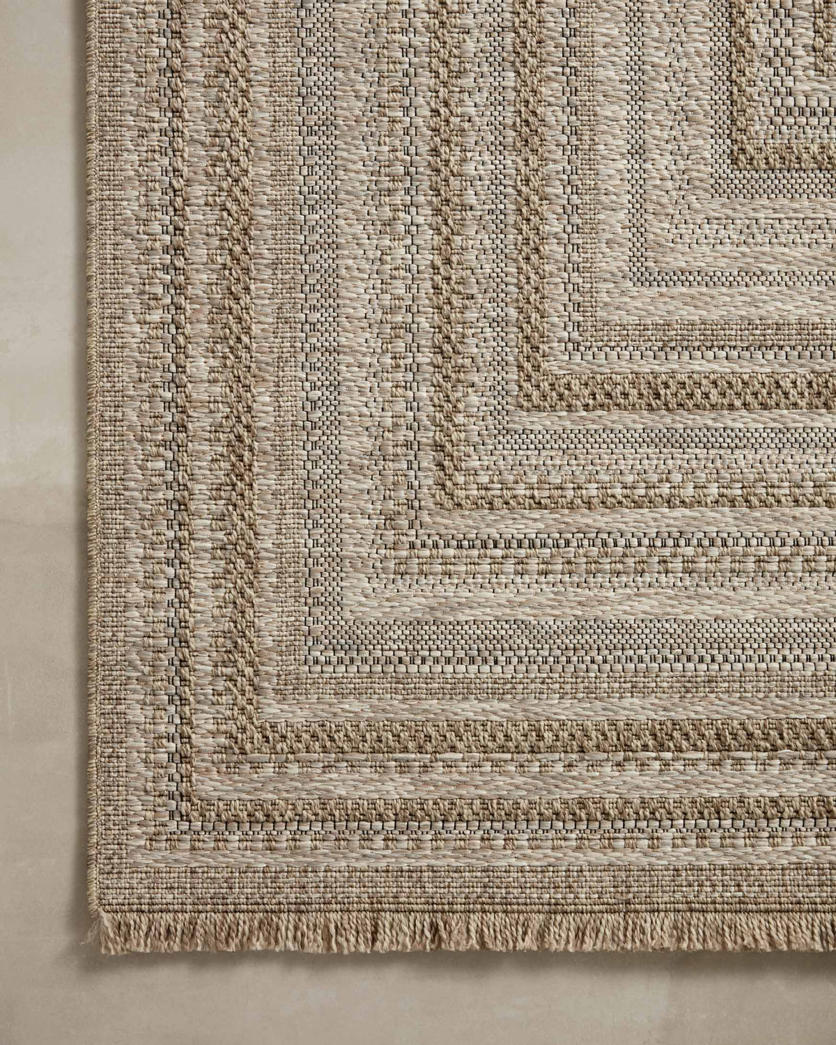 Natural area rug corner detail with layered geometric lines in beige and dark tan