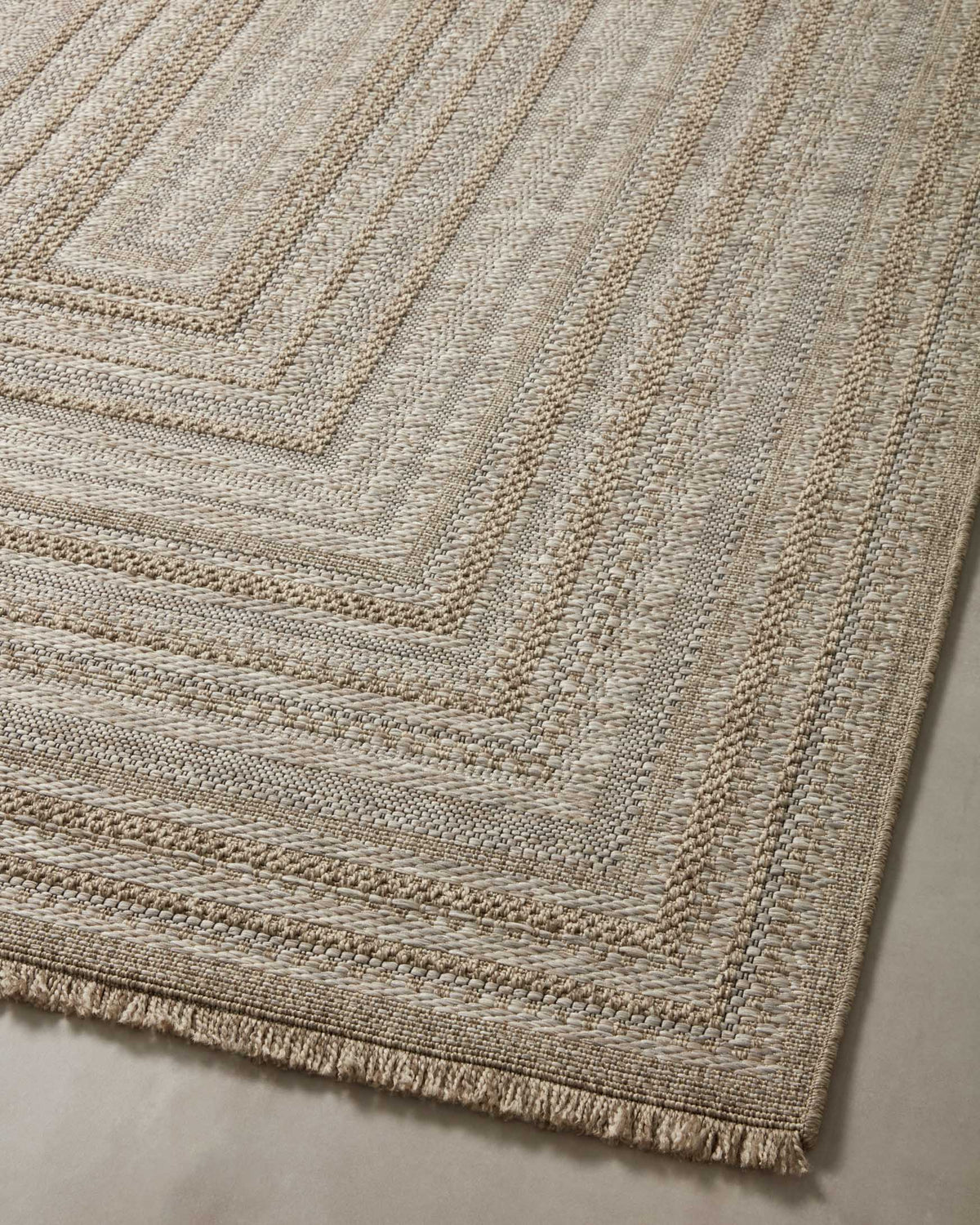 Natural geometric accent rug with stacked square motifs and short fringe along one edge