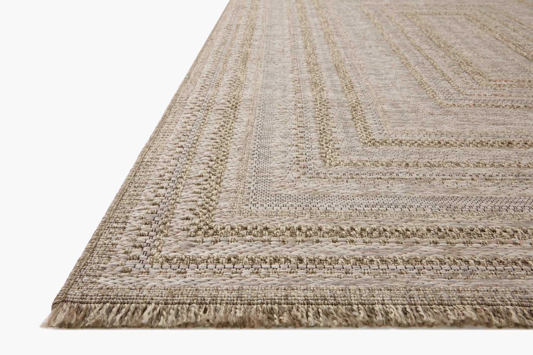 Natural woven area rug corner with geometric border and short fringe edging