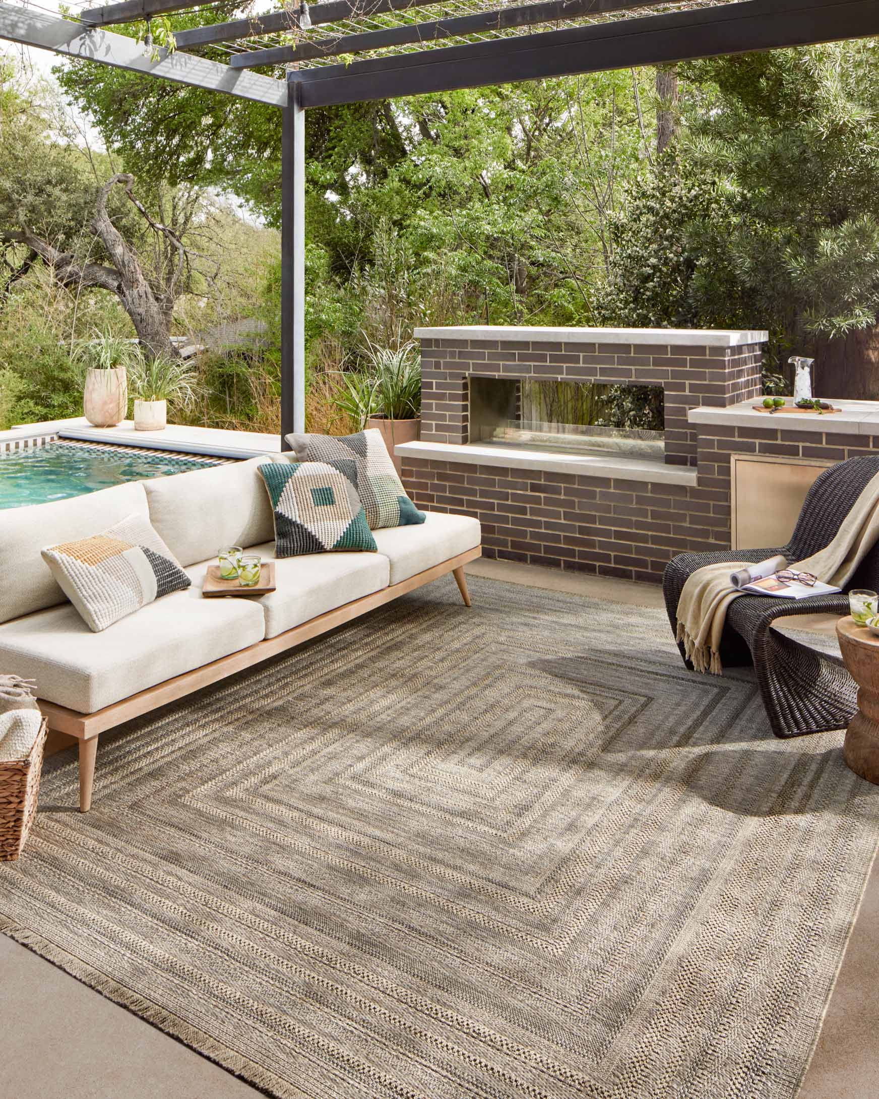 Natural geometric area rug with fringed edges, styled on a patio seating area