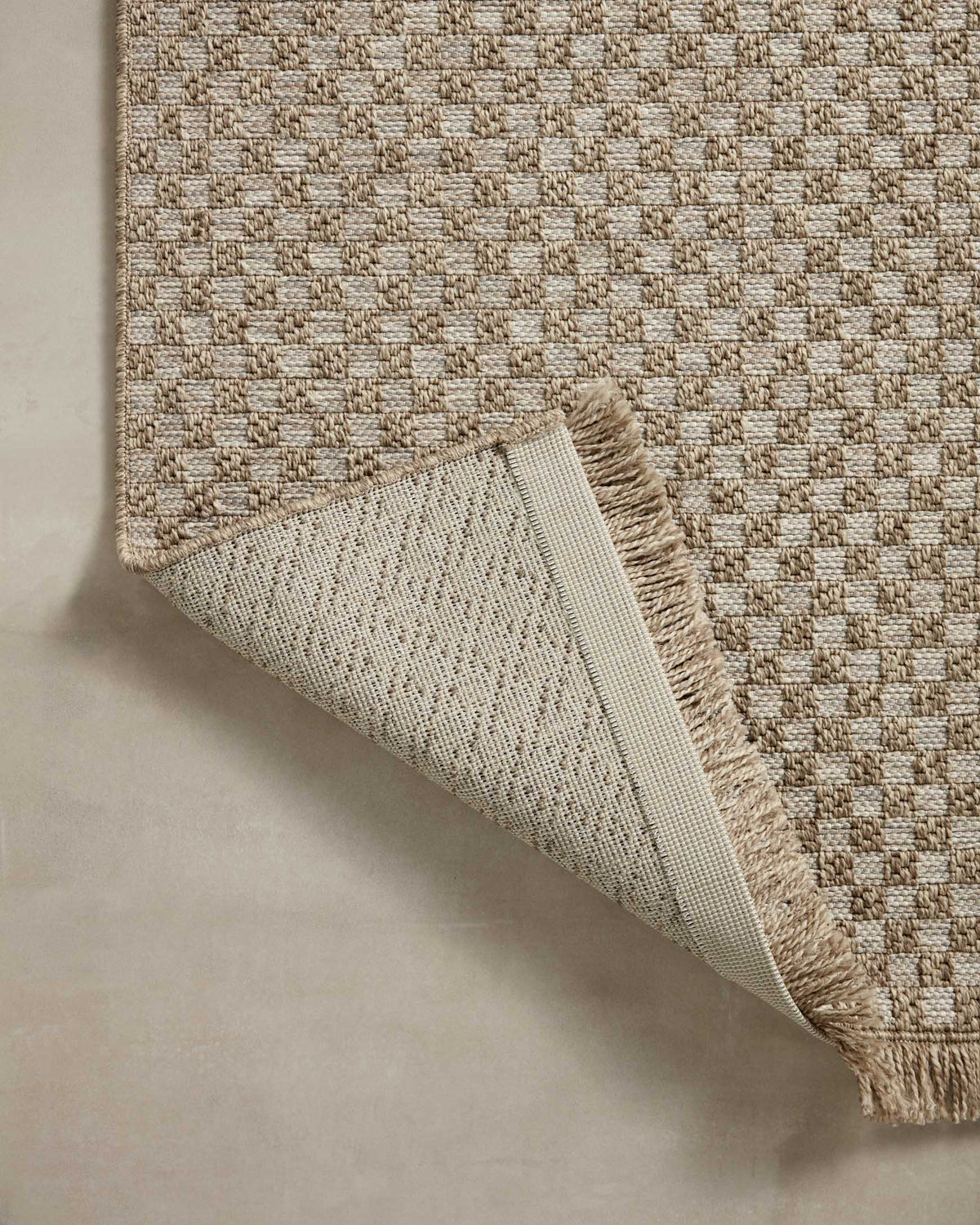 Natural area rug corner detail, lattice weave with short fringe and sewn edge