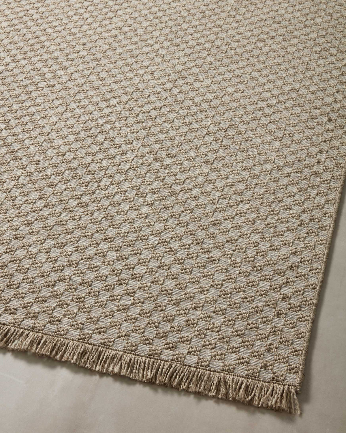 Natural woven area rug with repeating lattice pattern and fringe along the border