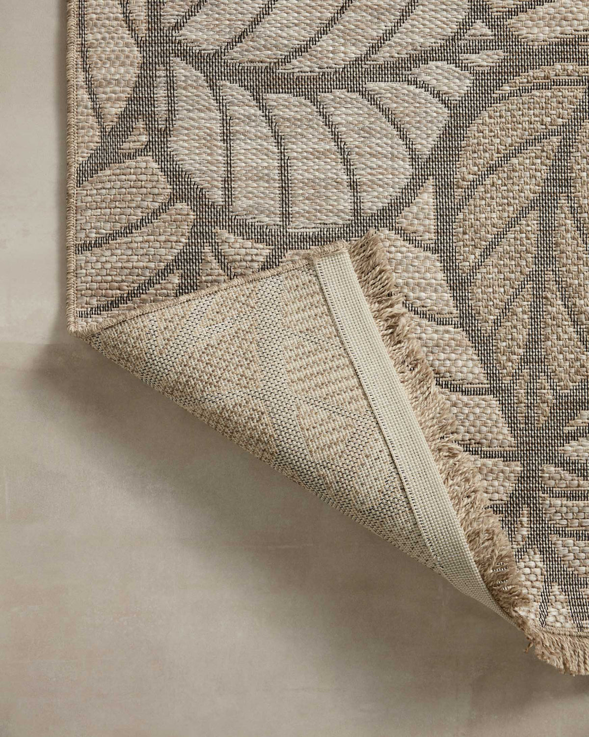 Natural area rug angled view with gray leaf pattern and fringed edge detail