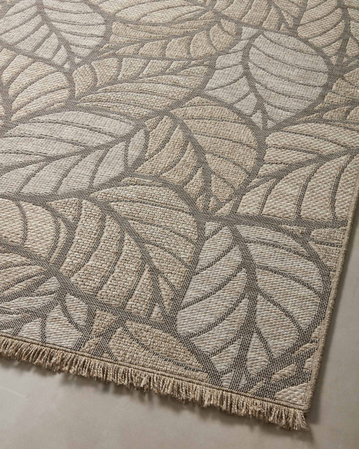 Natural area rug with gray leaf pattern and short fringed border, top view
