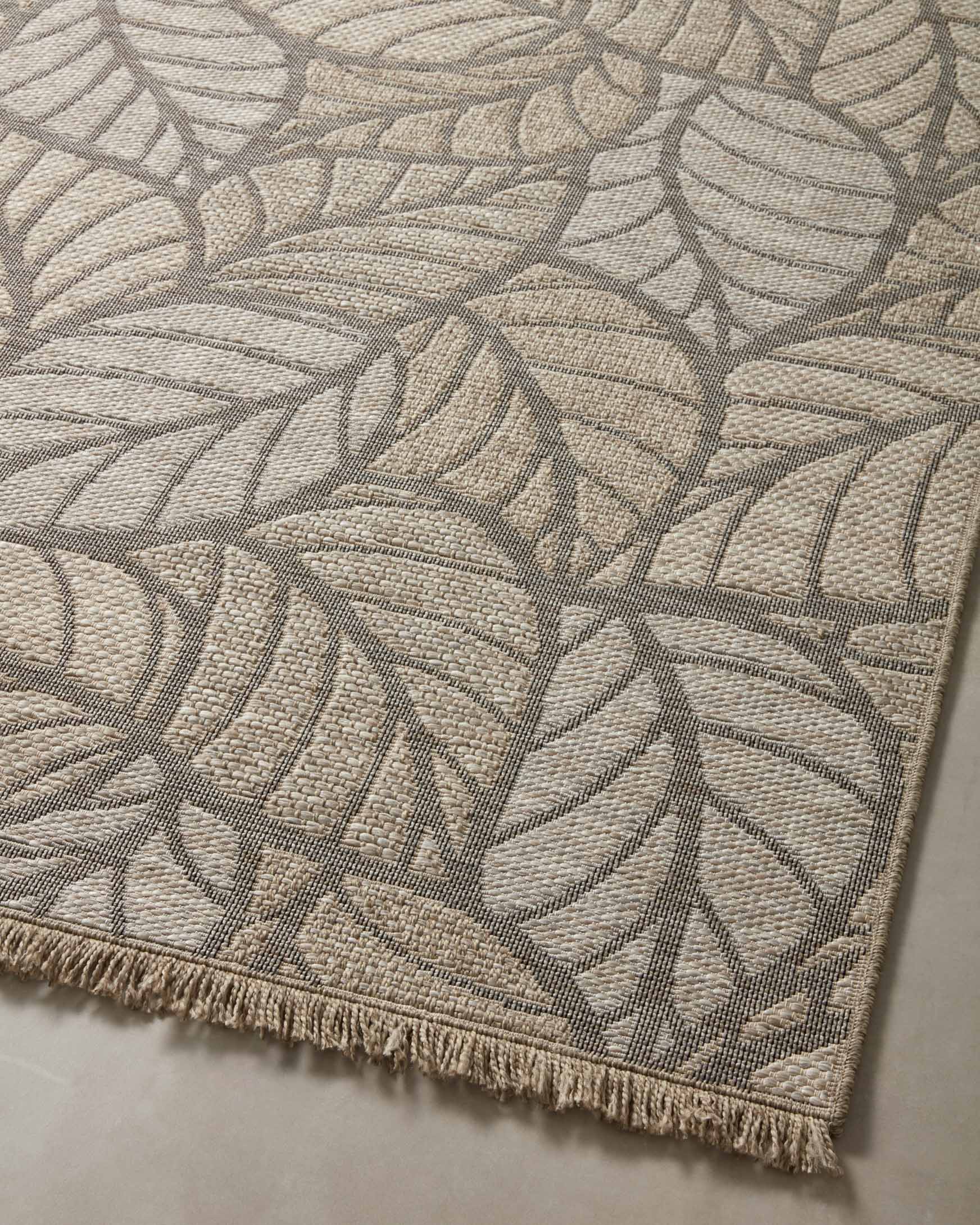 Natural area rug with gray botanical leaf design and short fringe on bottom edge