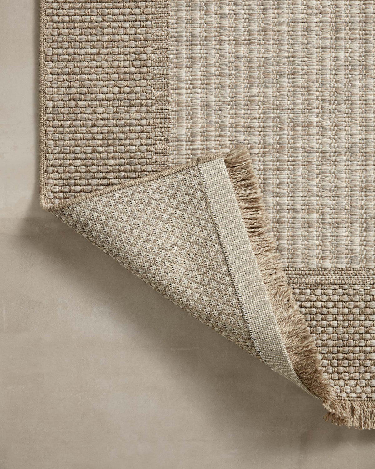 Natural woven area rug with rolled corner detail and fringe along the border