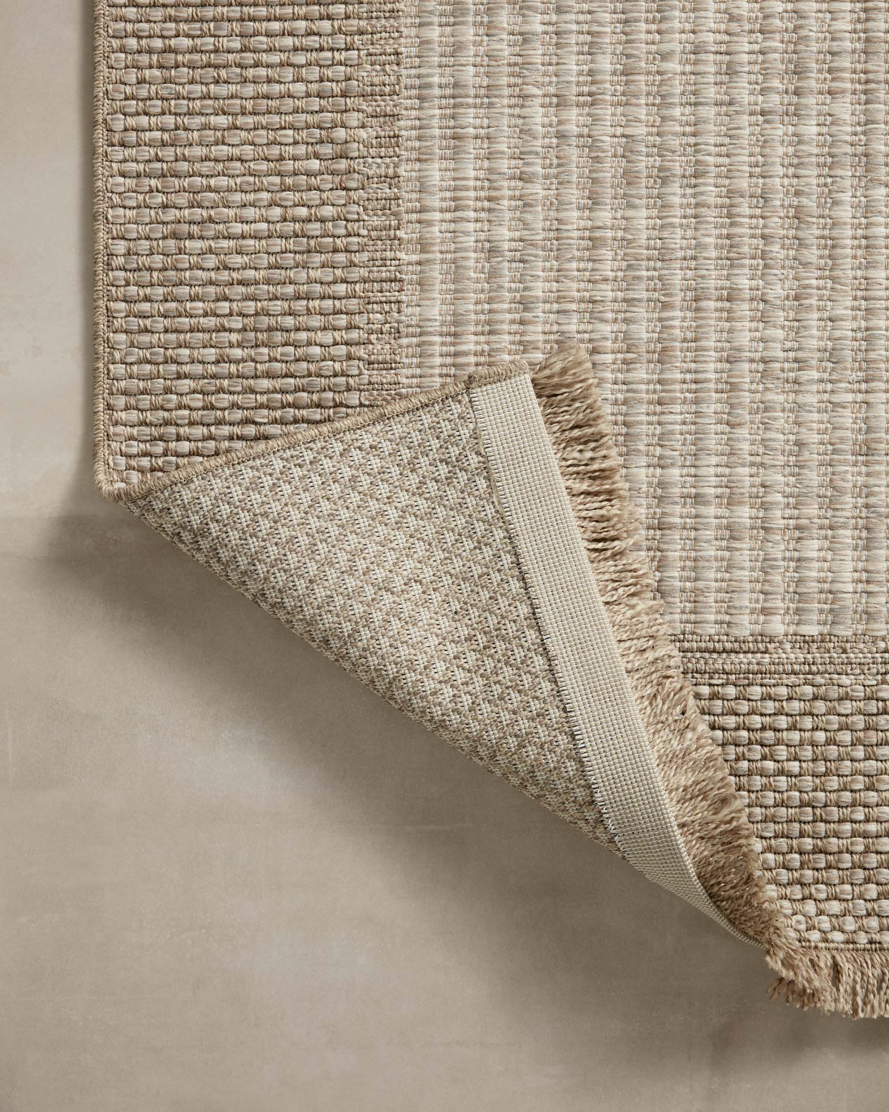 Natural area rug with folded edge showing flat woven texture and fringe