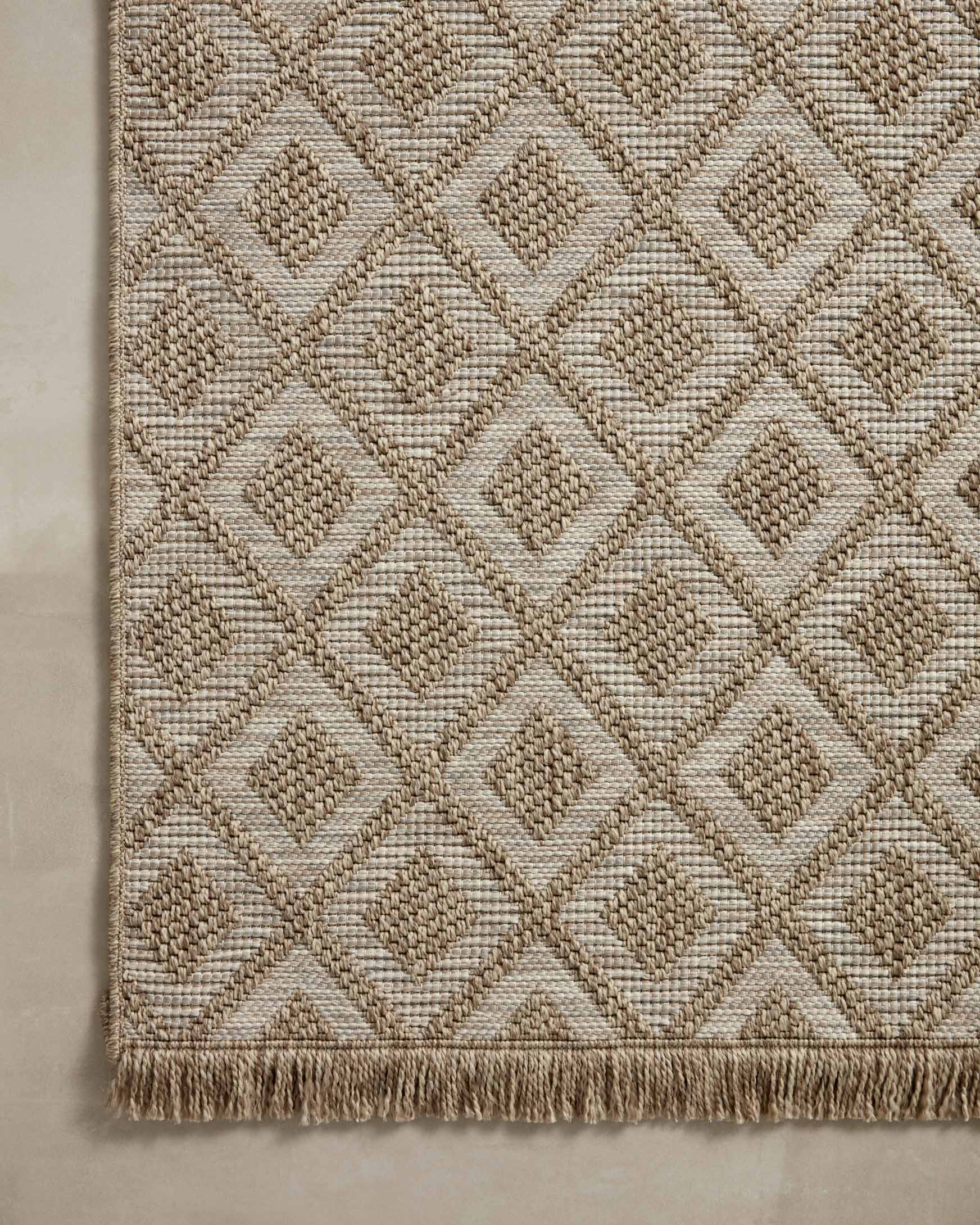 Beige textured rug corner with diamond lattice weave and short fringe