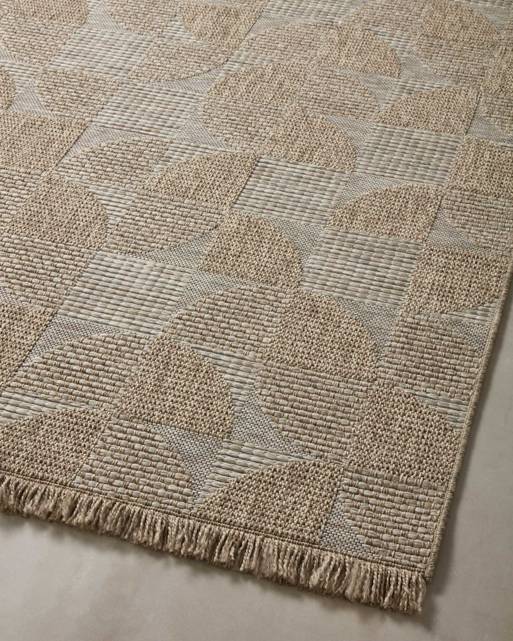 Natural patchwork area rug with repeating geometric shapes and fringed border
