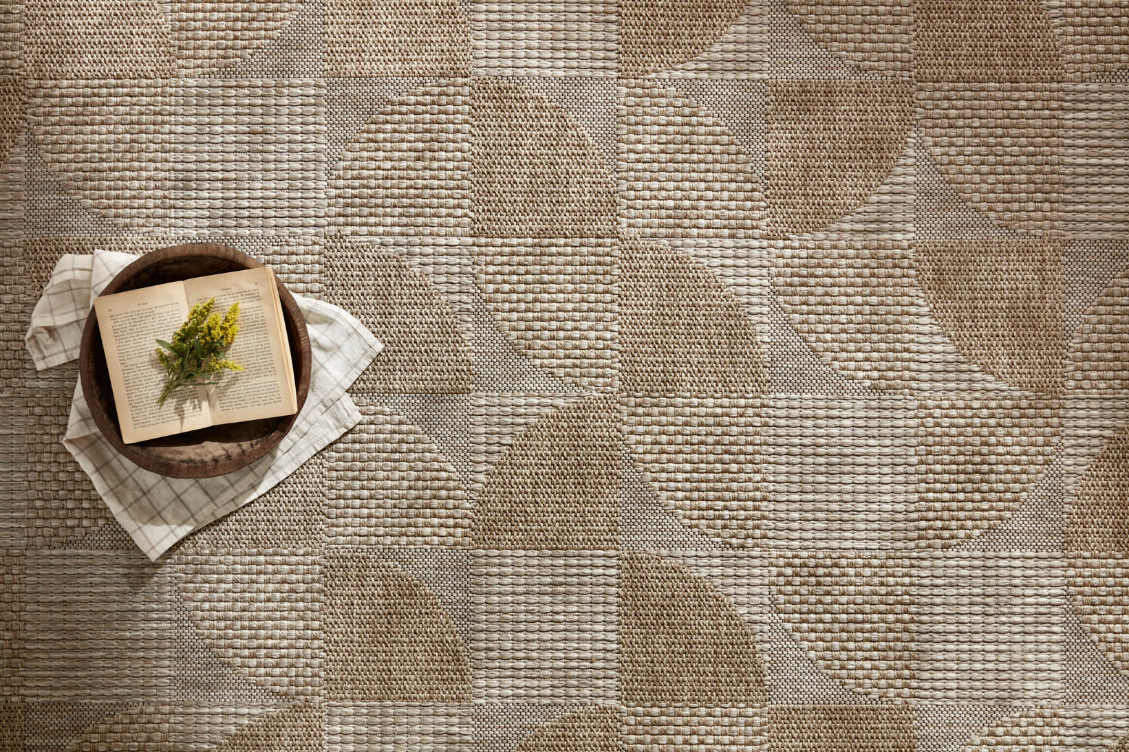 Natural woven area rug with abstract patchwork pattern and textured surface