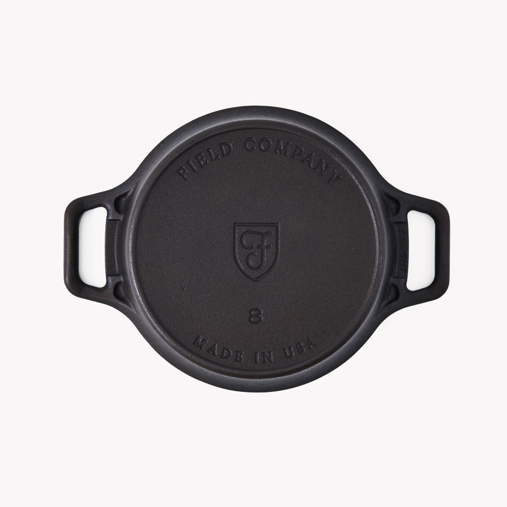 Black cast iron lid with Field Company shield logo and handle grips