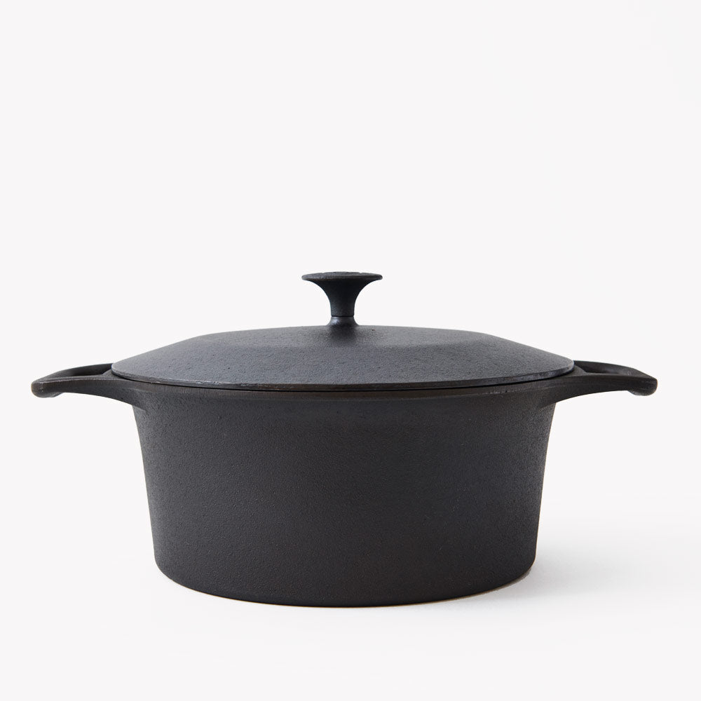Black cast iron dutch oven with domed lid knob and side handles