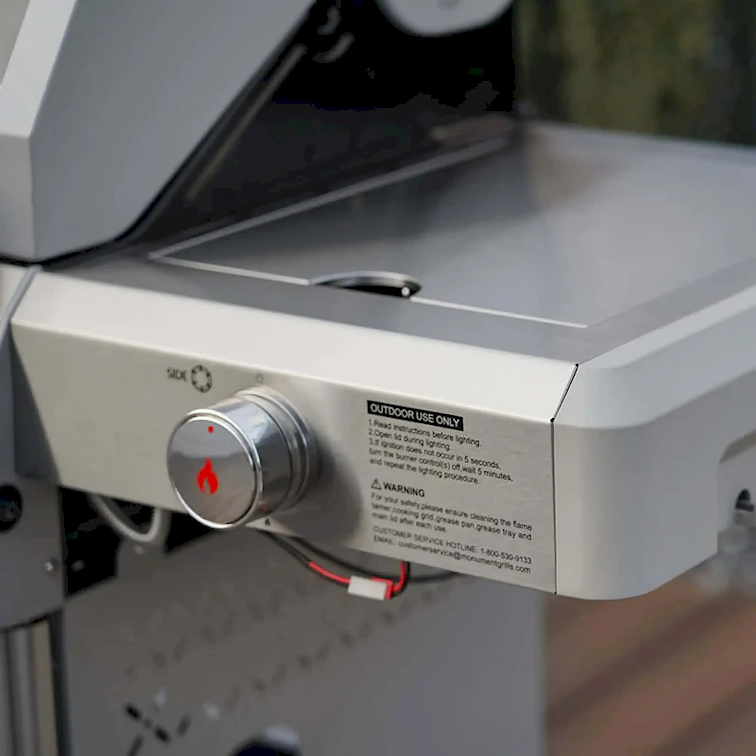 Stainless steel propane grill side control panel with knob and warning label
