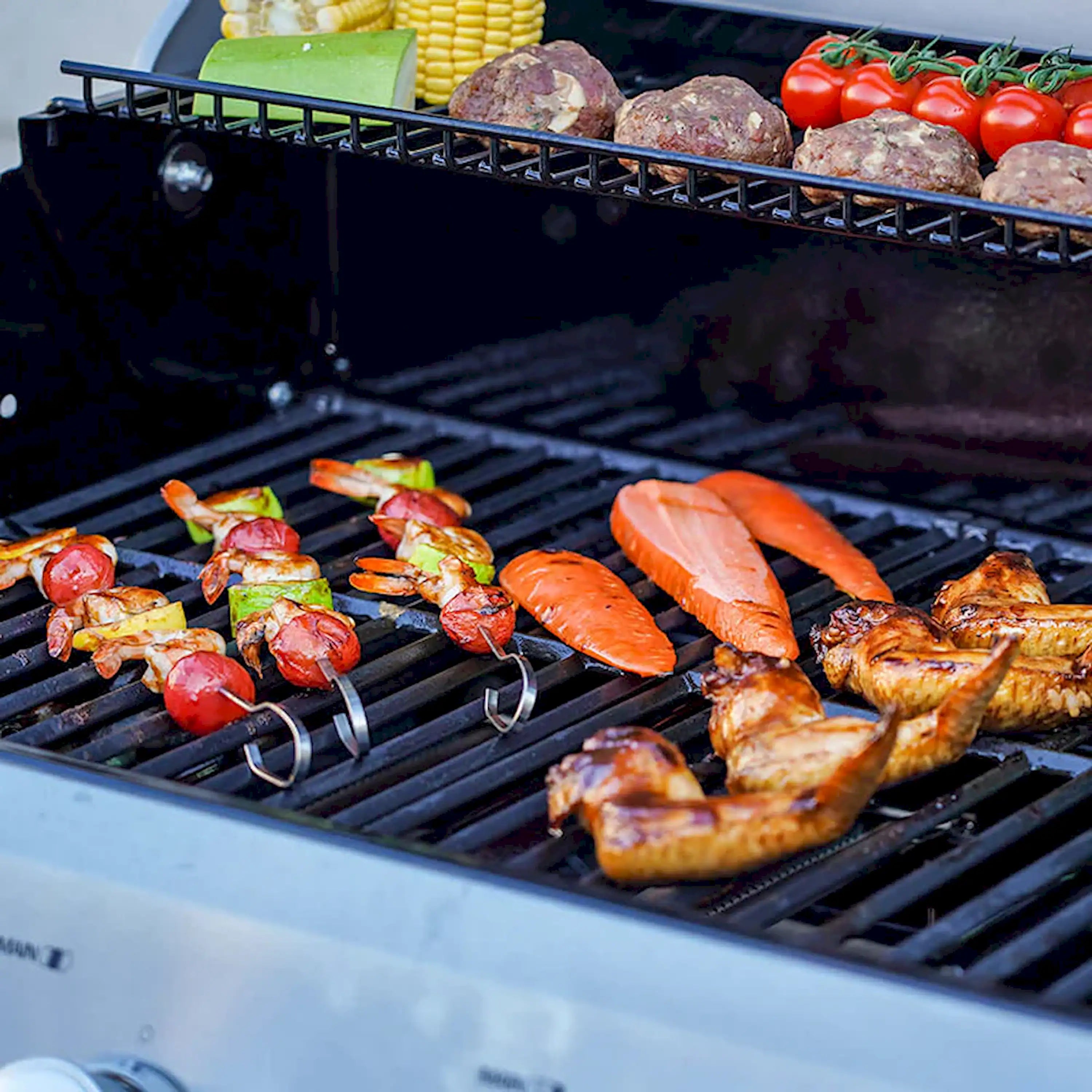 Propane grill with multiple meats and vegetables on open cooking grates