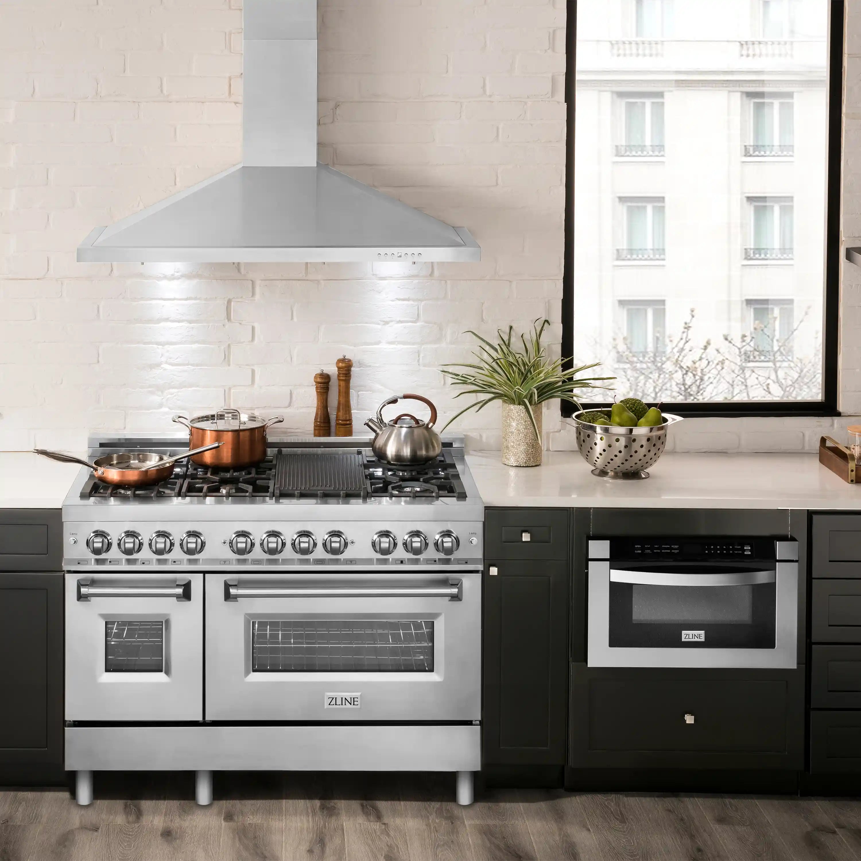 Stainless steel range hood above a stainless and black range in a kitchen