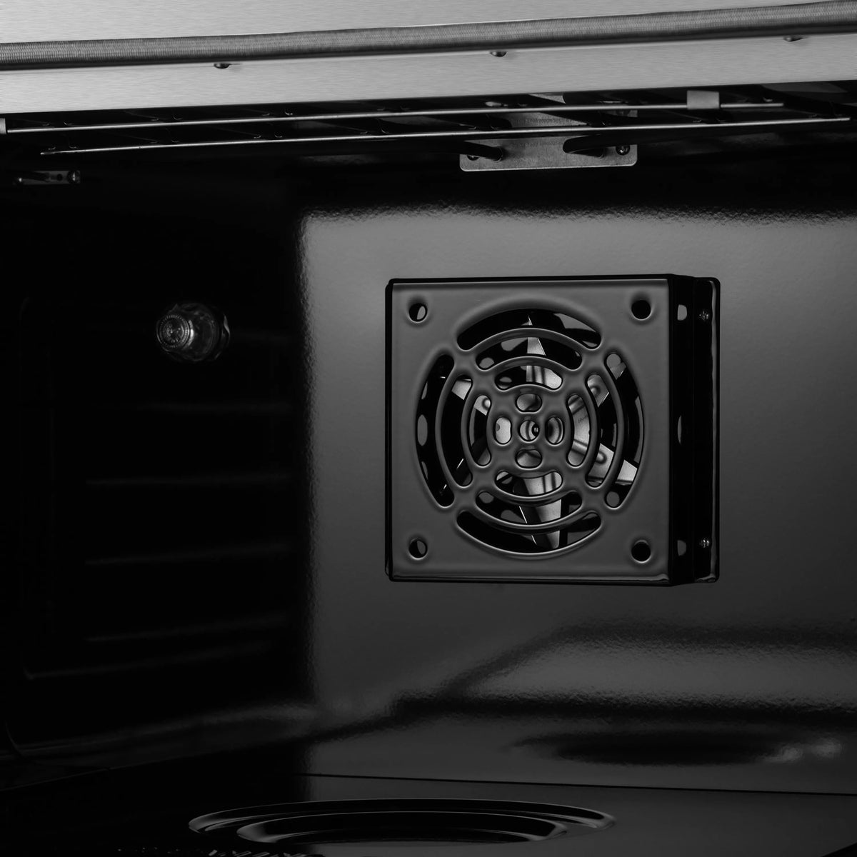 Black oven door interior with round convection fan vent in back panel