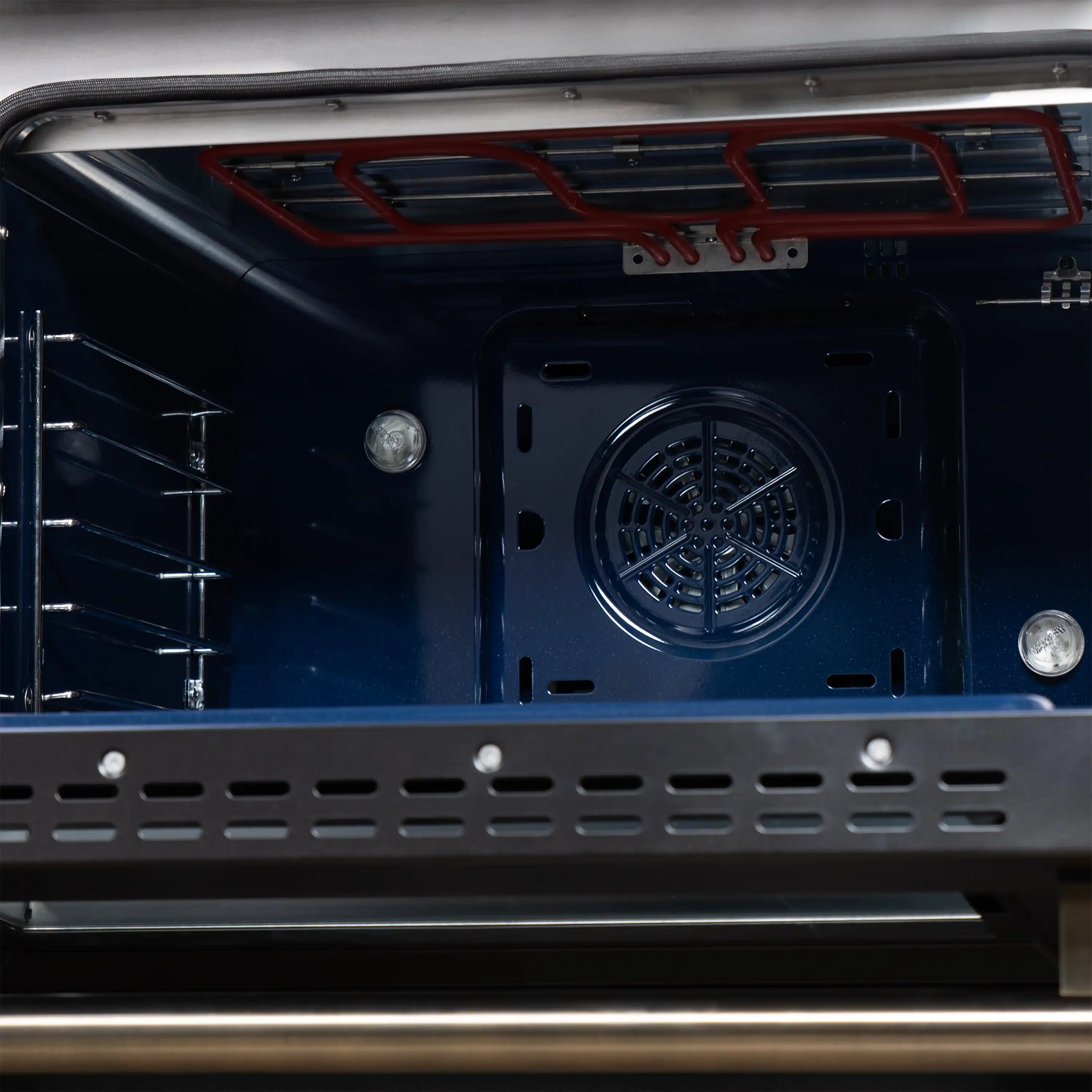 Black convection oven cavity with circular fan vent and wire rack rails