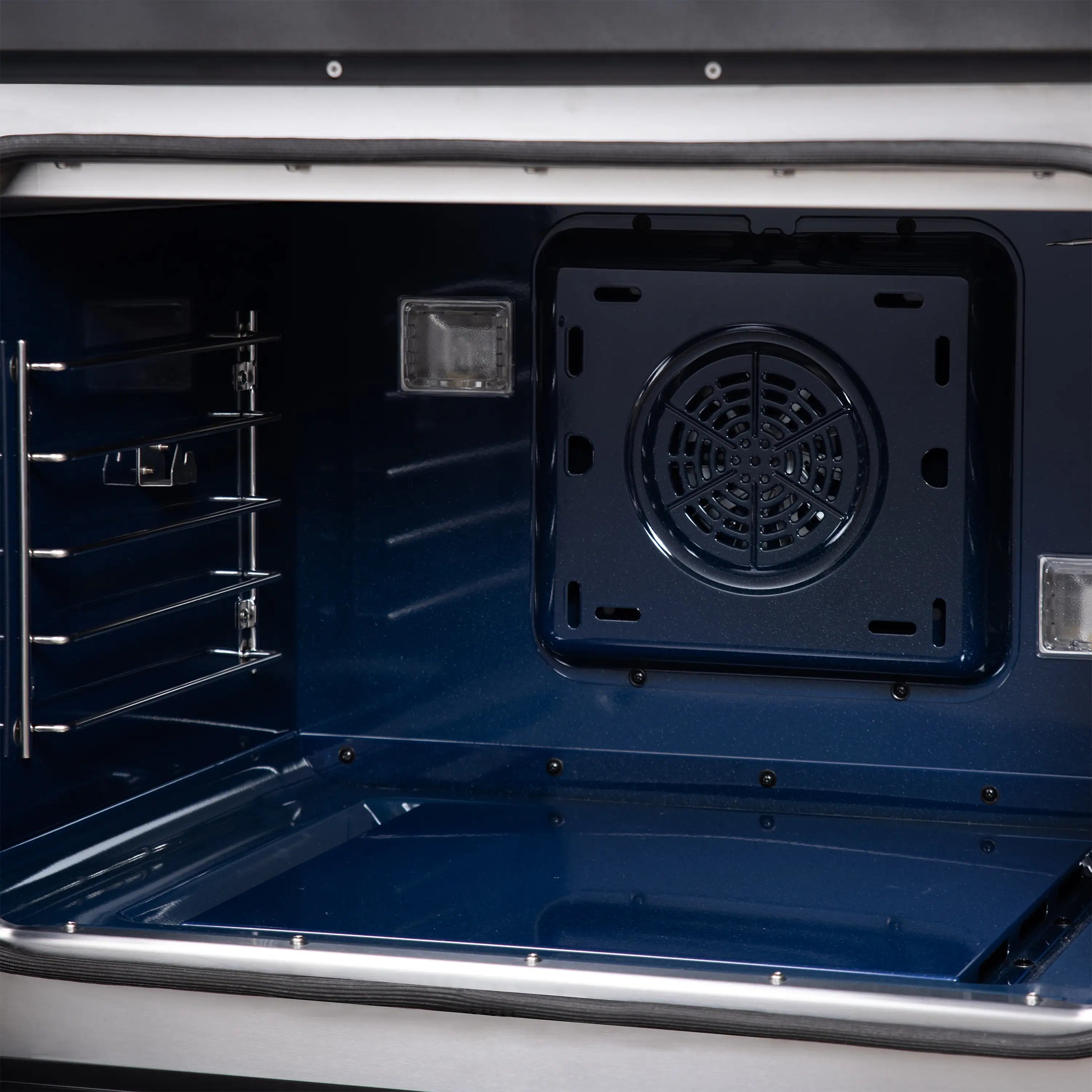 Dual fuel range oven interior with blue back panel and circular ventilation plate