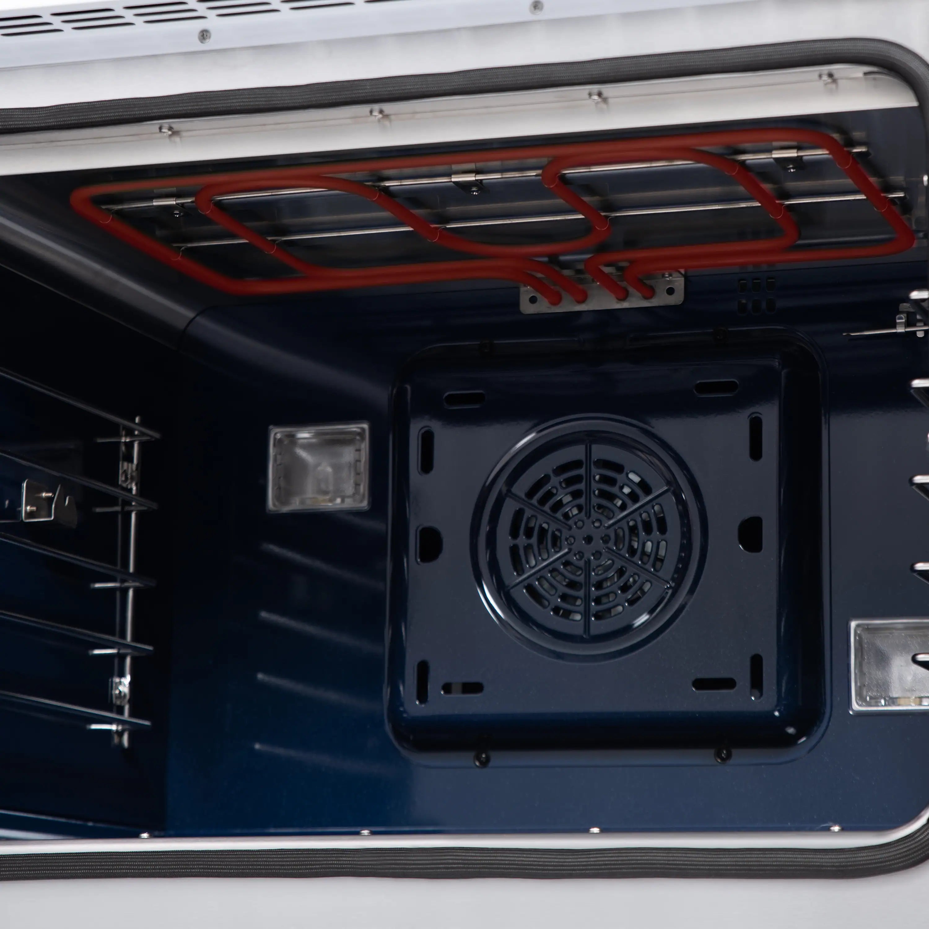 Dual fuel oven interior with exposed red heating element wiring and round fan vent.