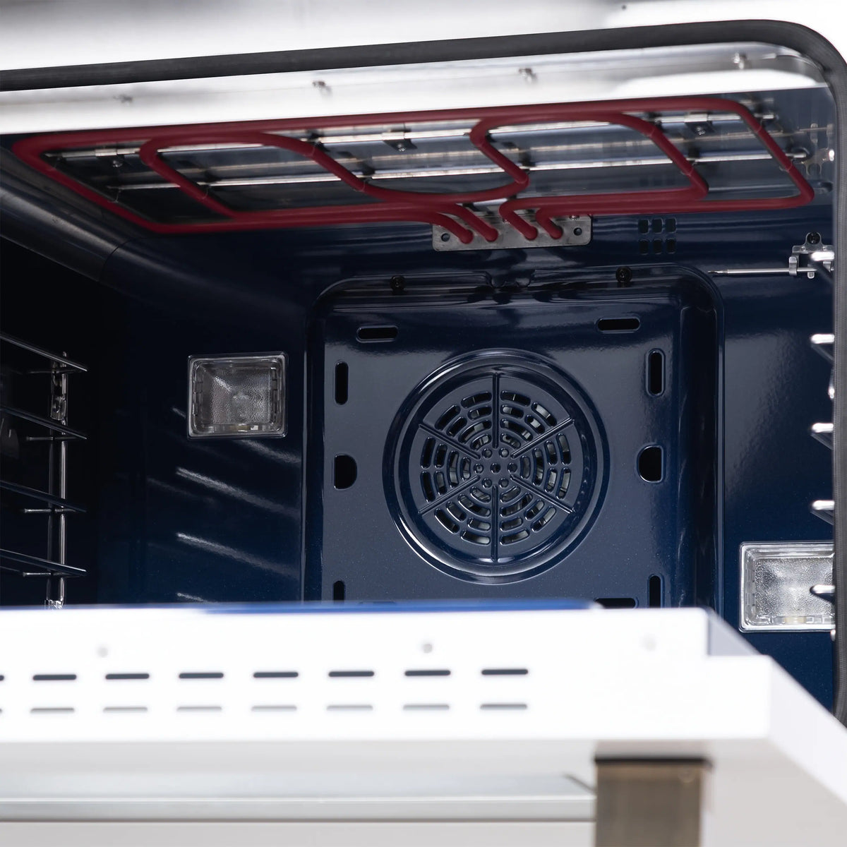 Gas range oven interior with circular fan vent and red broil shield