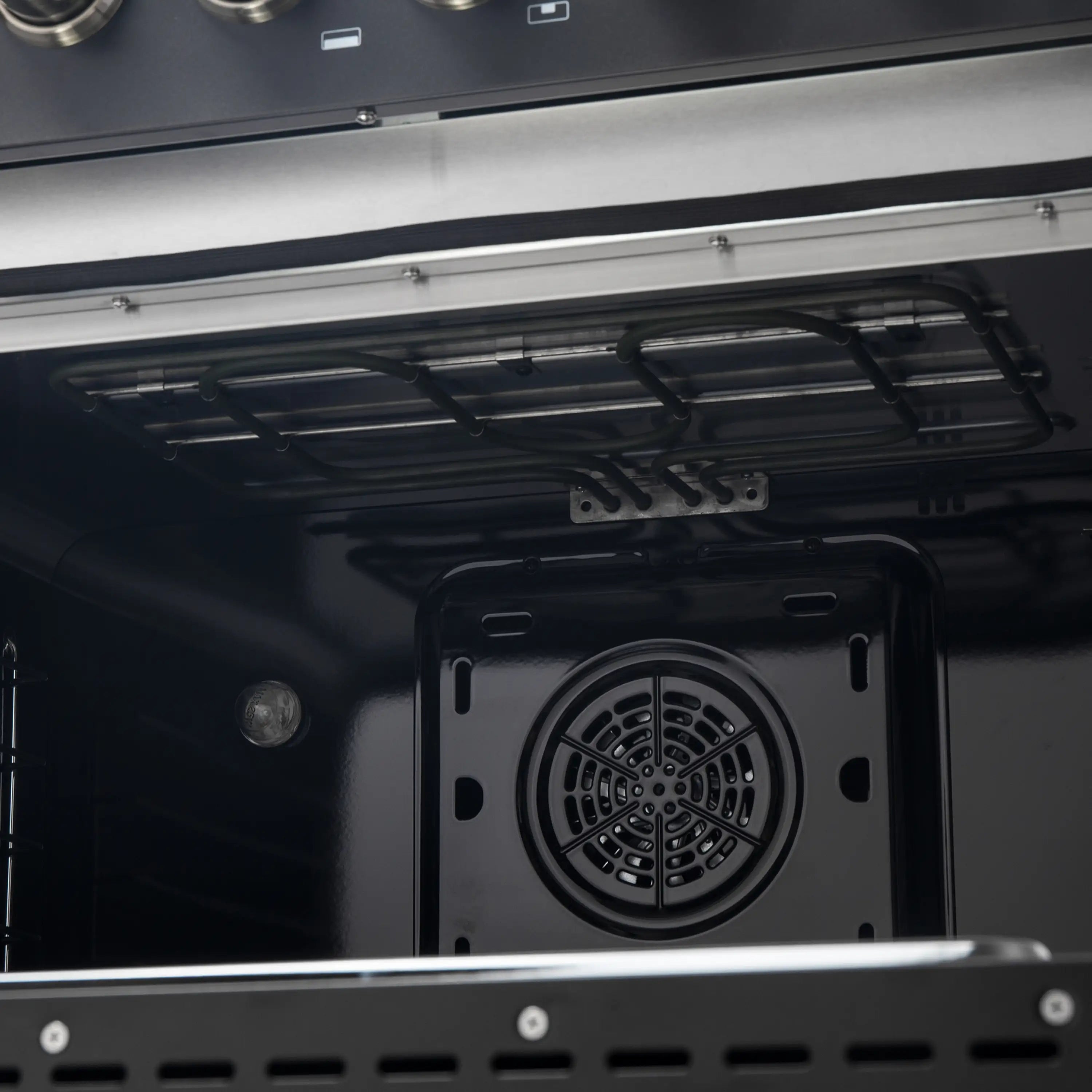 Dual fuel range oven interior with circular convection fan vent at back wall