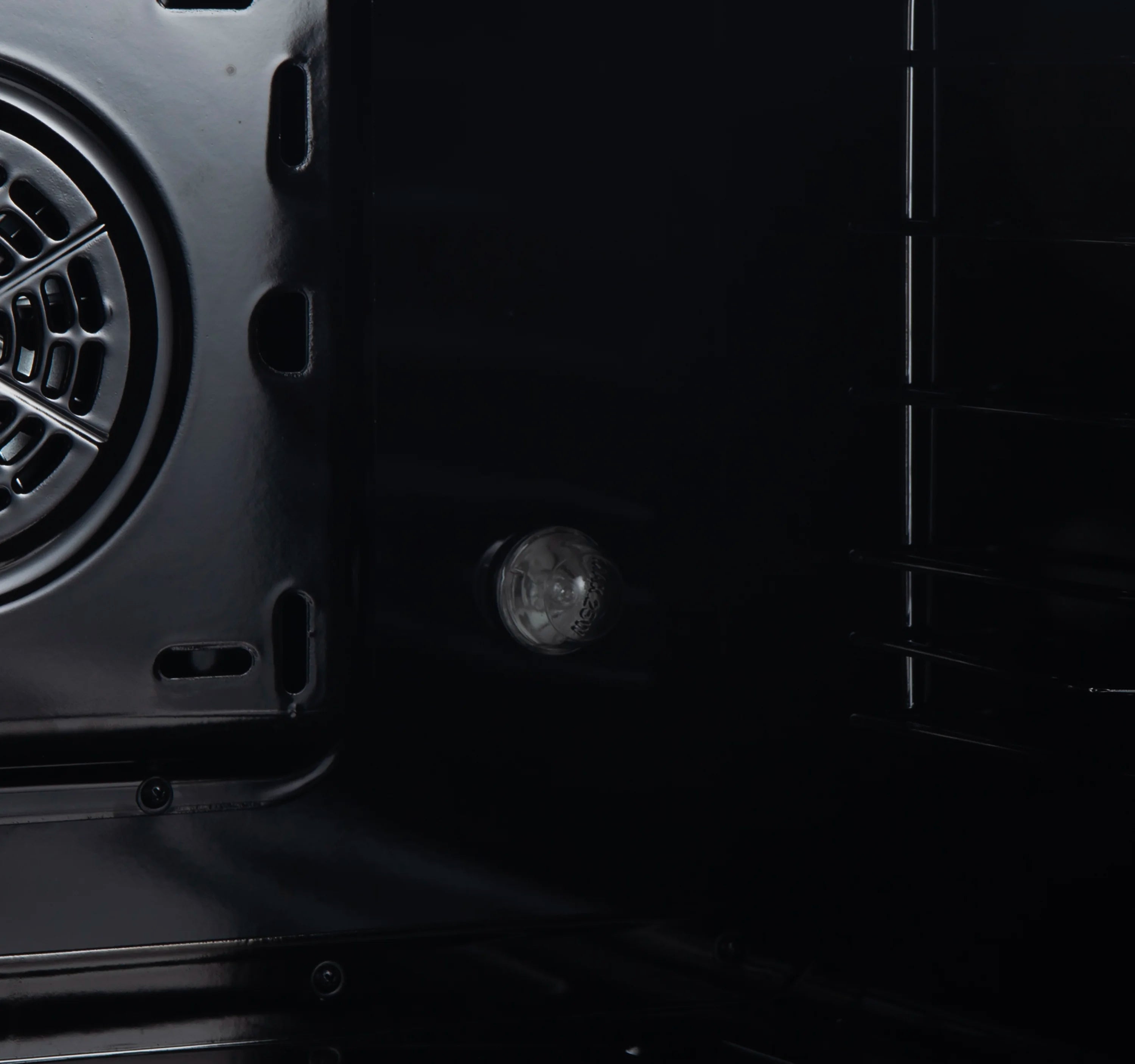 Dual fuel range oven interior wall panel with round oven light and vents.