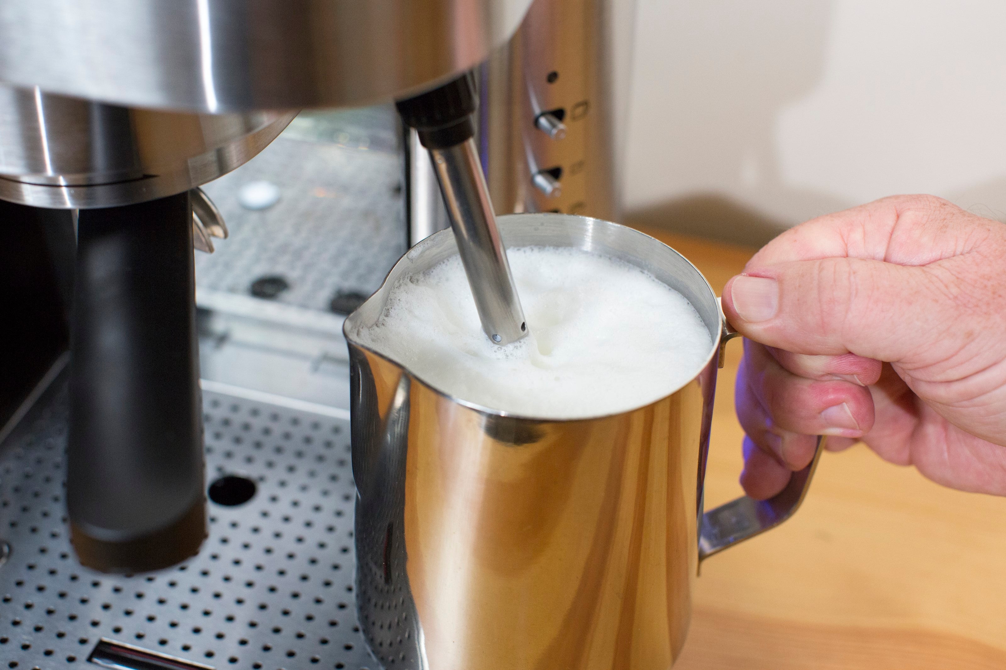 Espressione espresso machine dispensing into golden mug held by hand