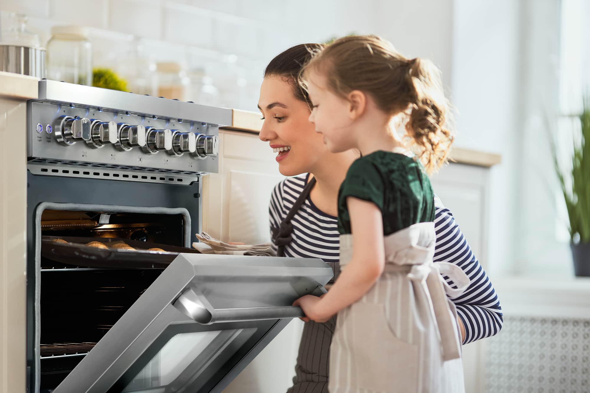 Stainless steel gas range with open oven door and multiple burner control knobs