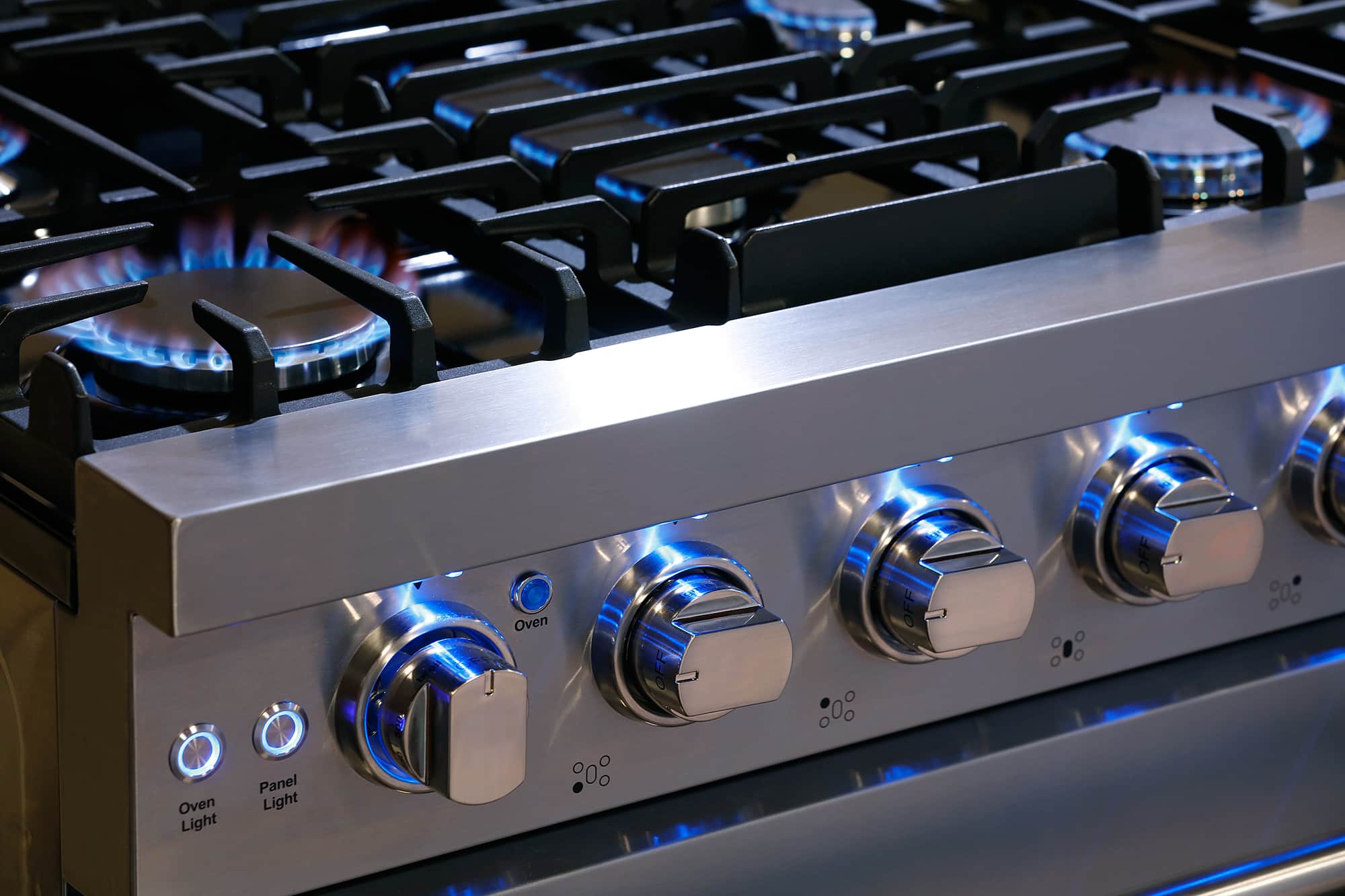 Stainless gas range control knobs with blue flames on burners