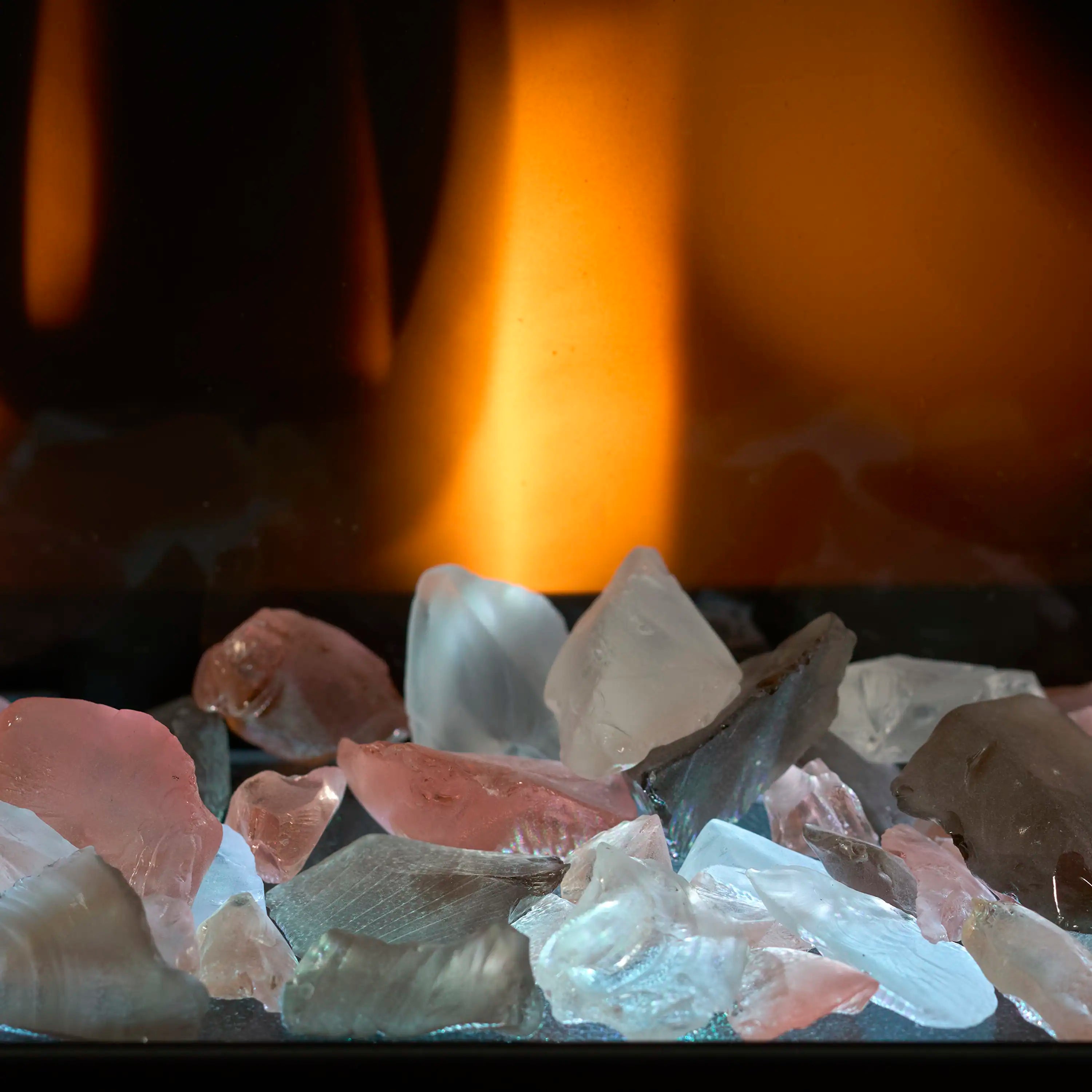 Electric fireplace ember bed close-up with blue and clear rocks behind orange flames