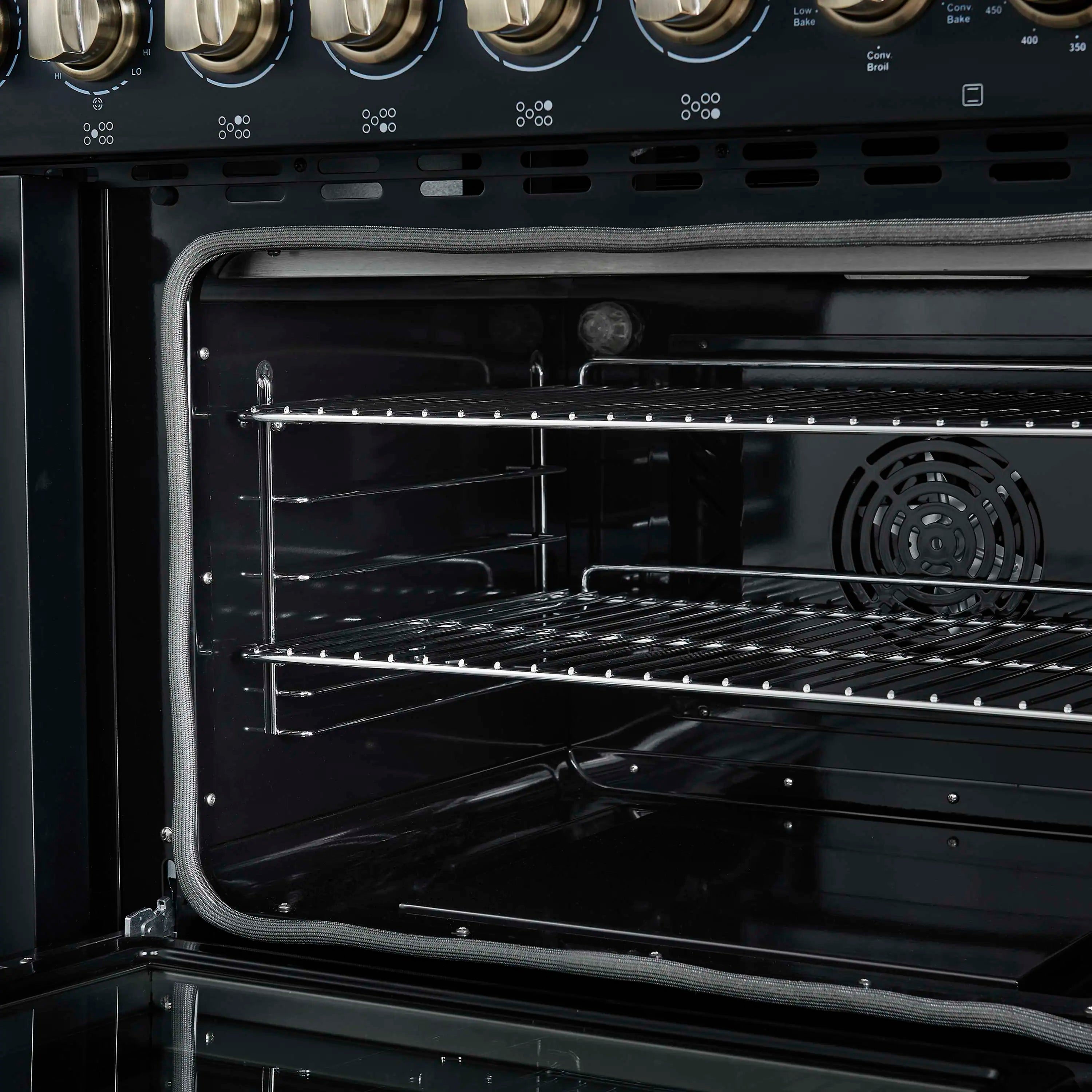 Black oven interior with lower rack, side rails, and fan behind the center panel.