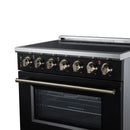 Close view of black oven and stainless handle with brass burner control knobs