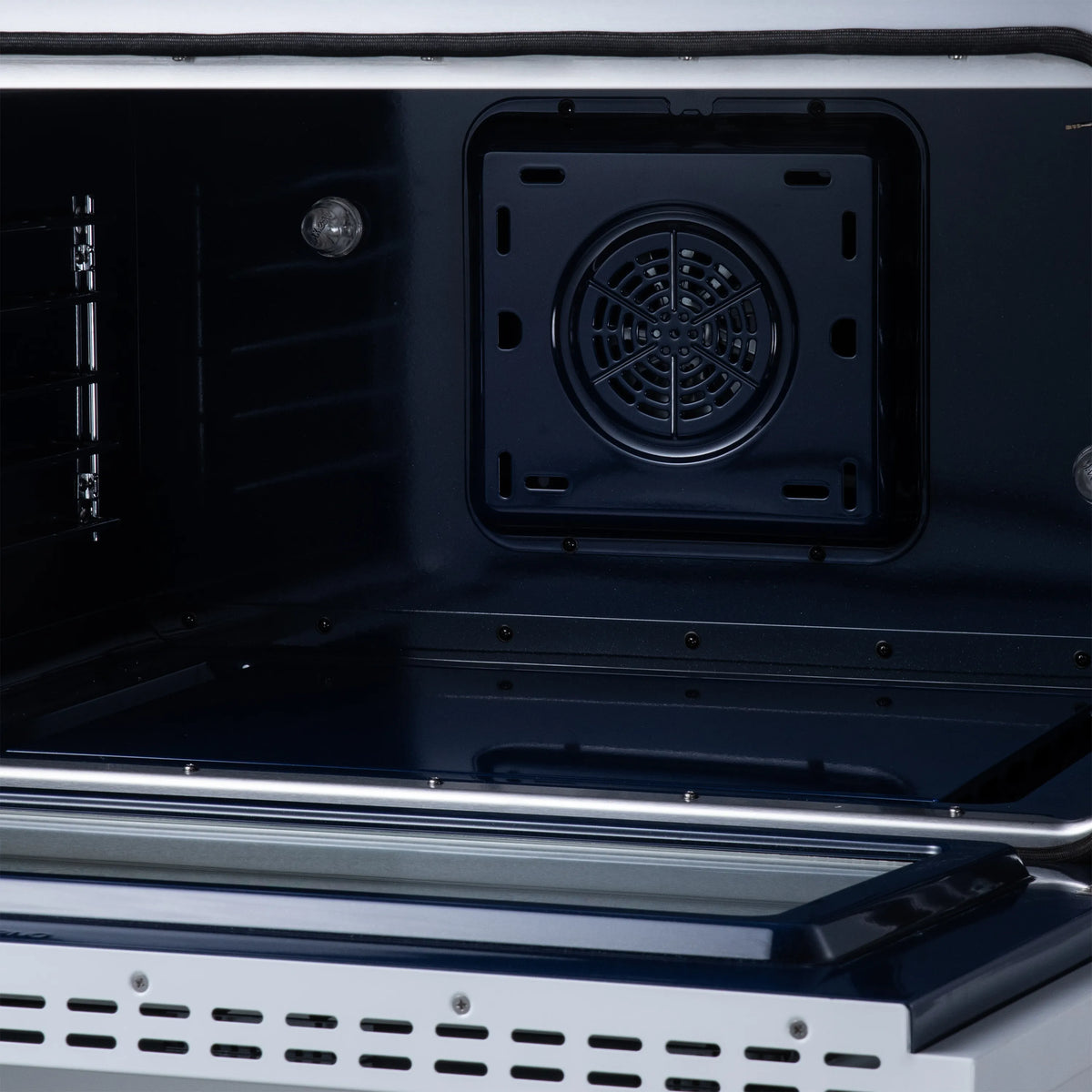 Oven interior with round convection fan vent opening on black back panel inside range
