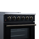 Black electric range control panel with gold knobs and oven door handle