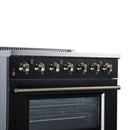 Freestanding electric range with black cooktop, brass knobs, and oven window