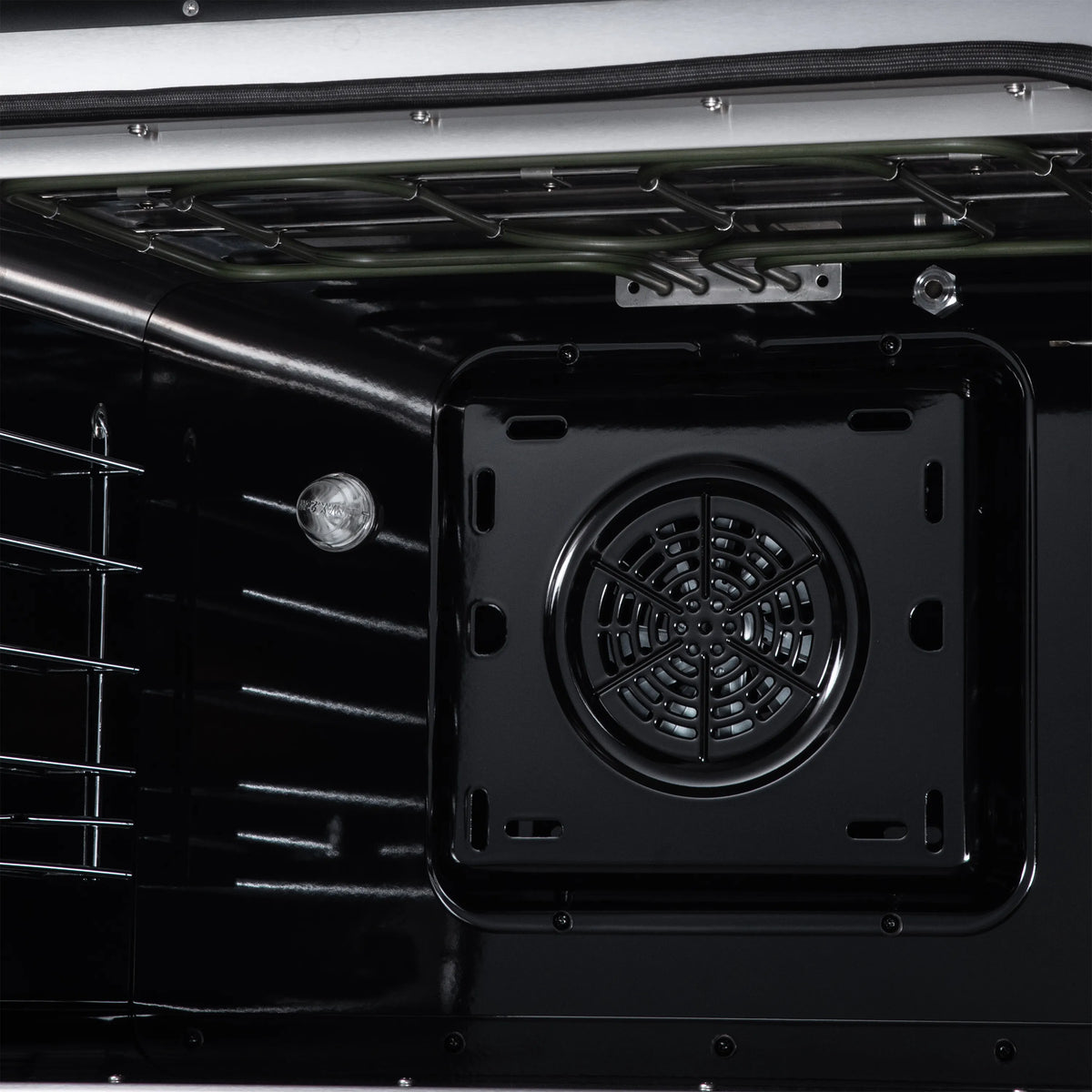 Convection oven interior with circular fan vent on the back wall and metal racks