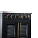 Black electric range with dual oven doors and brass control knobs on stainless backguard