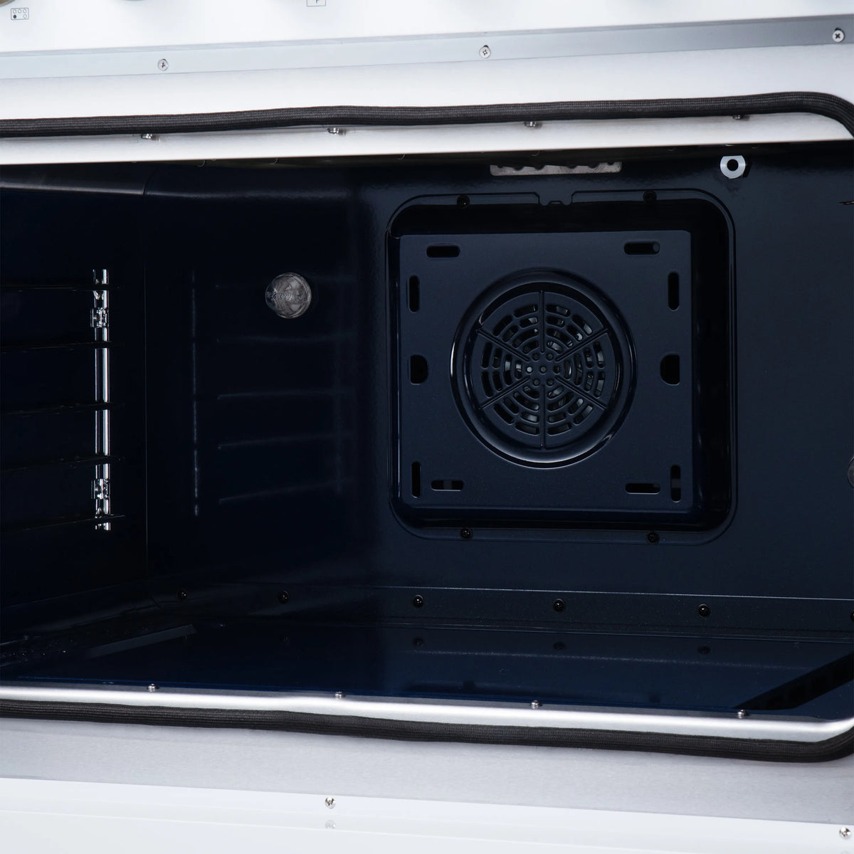 Convection oven interior view of circular rear fan vent and metal oven frame