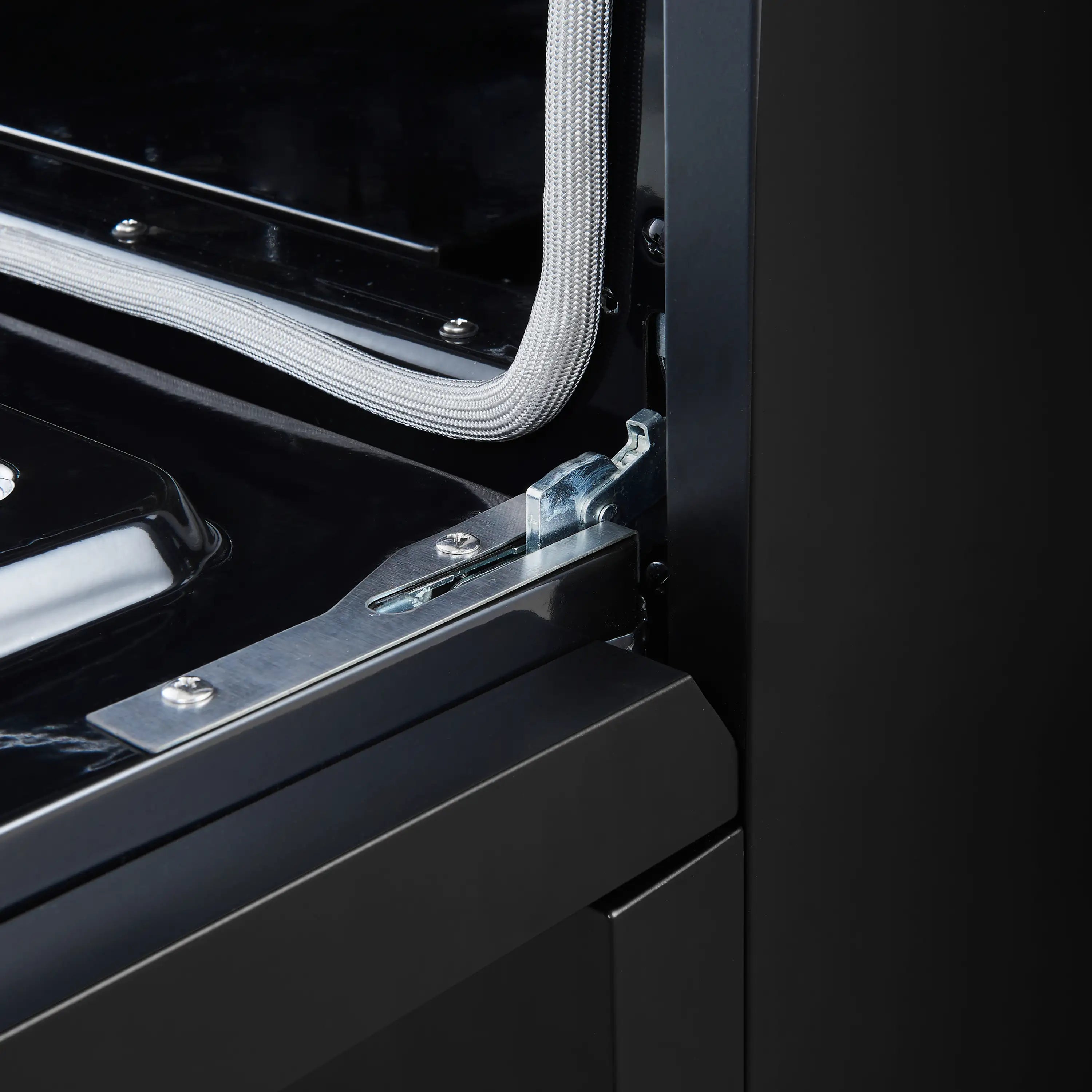 Electric range oven door hinge and gasket area in black with metal hardware