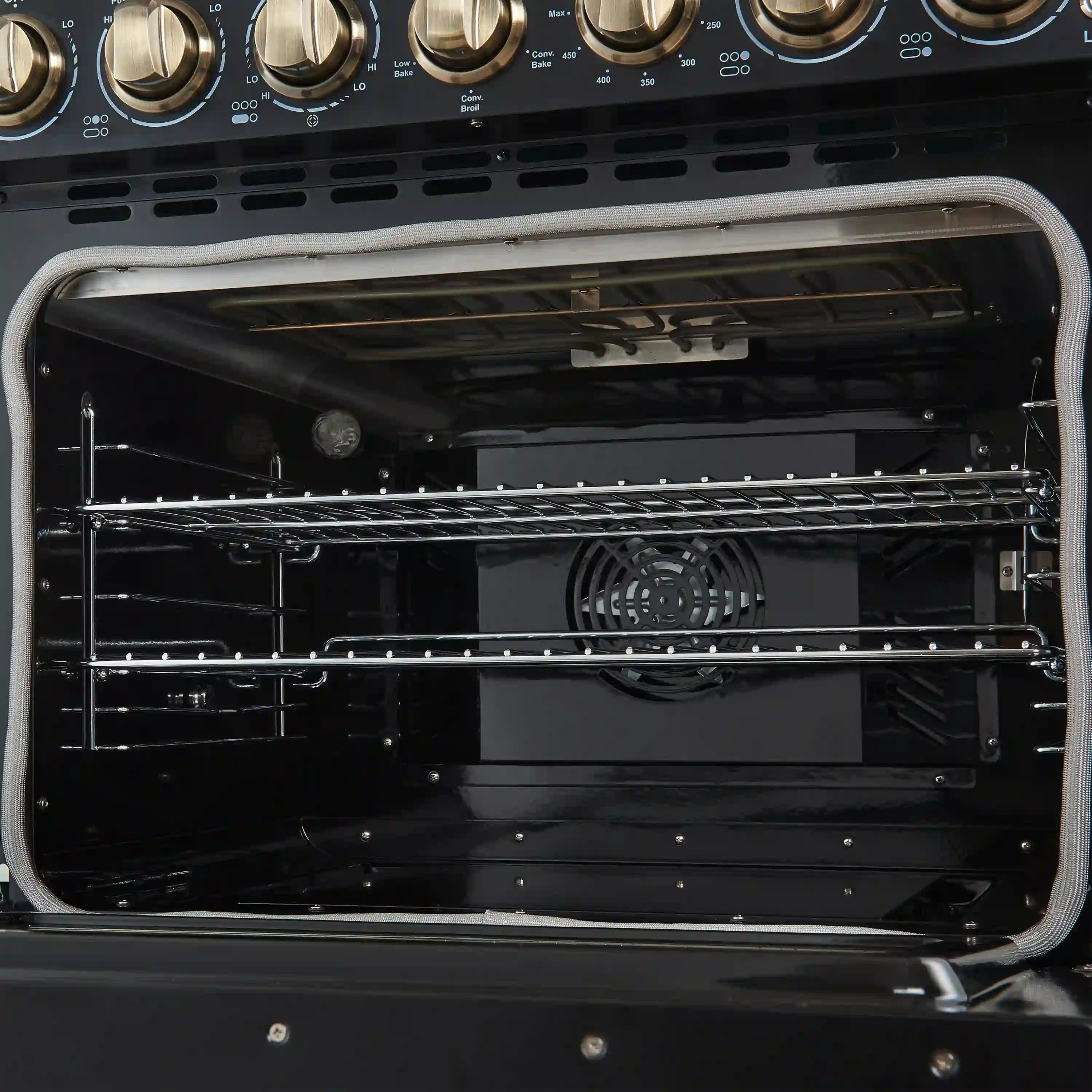 Open oven interior with fan and wire racks inside a black electric range