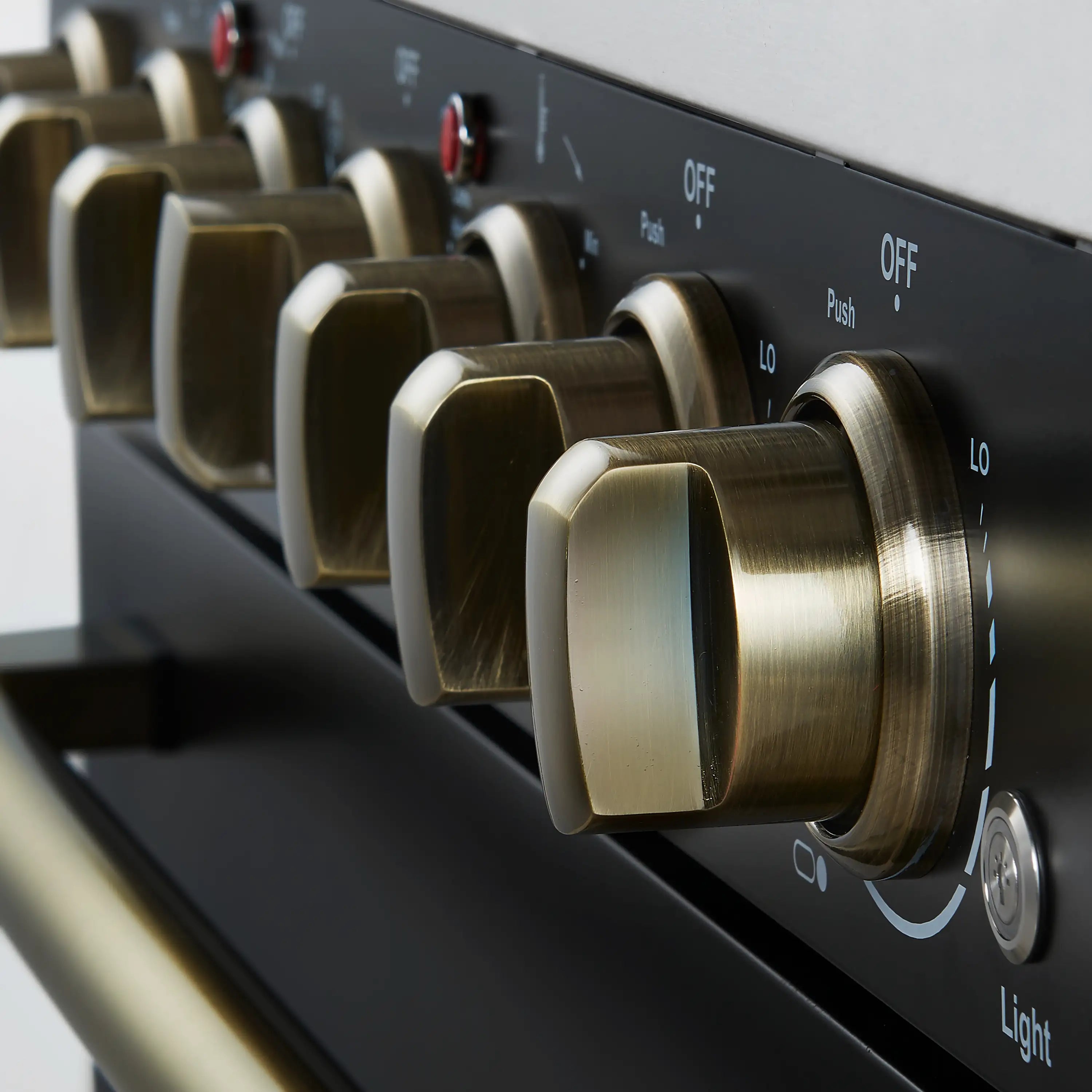 Antique brass control knob on black range with push-to-turn indicator marks.