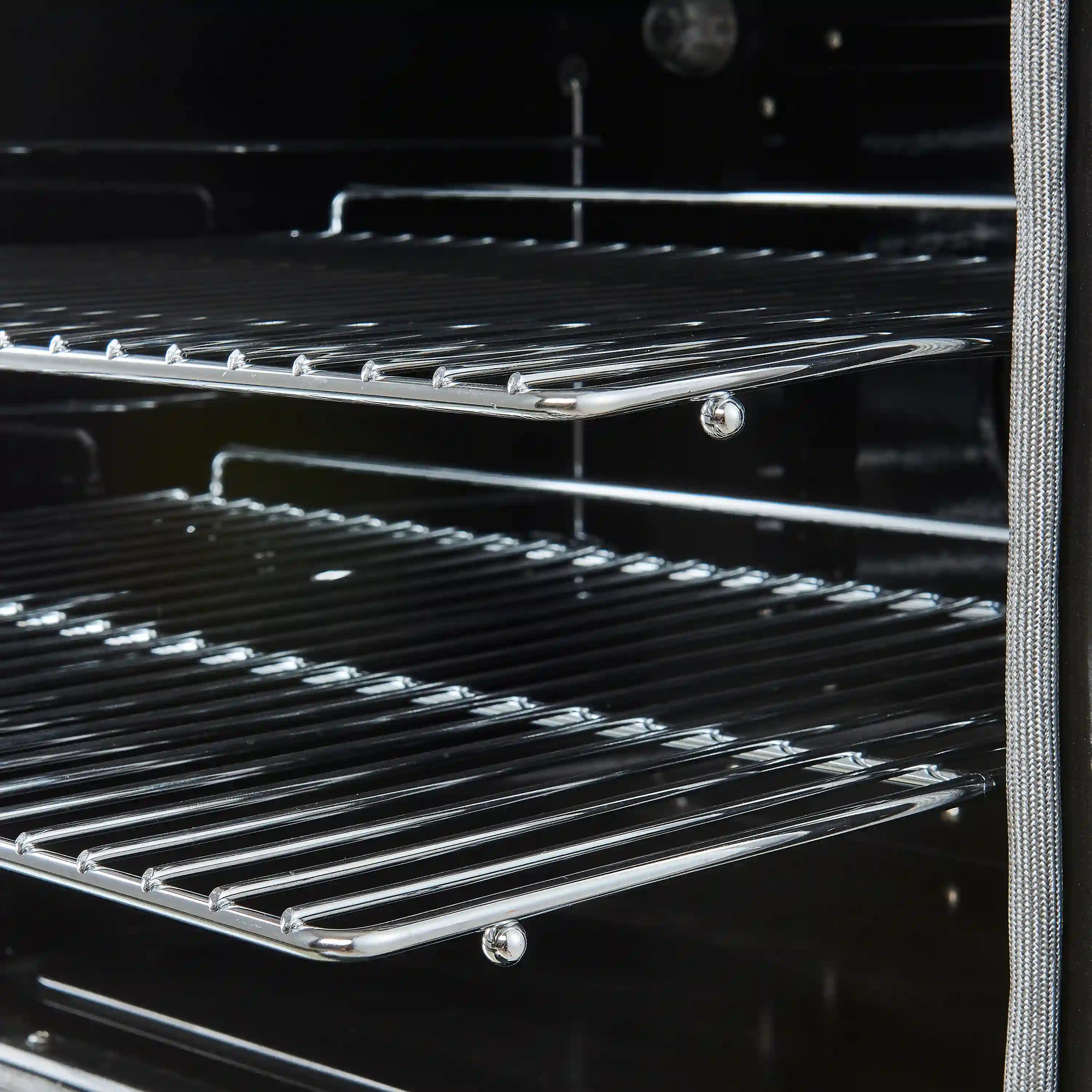 Wire oven racks inside a white electric range with dark baked-enamel interior