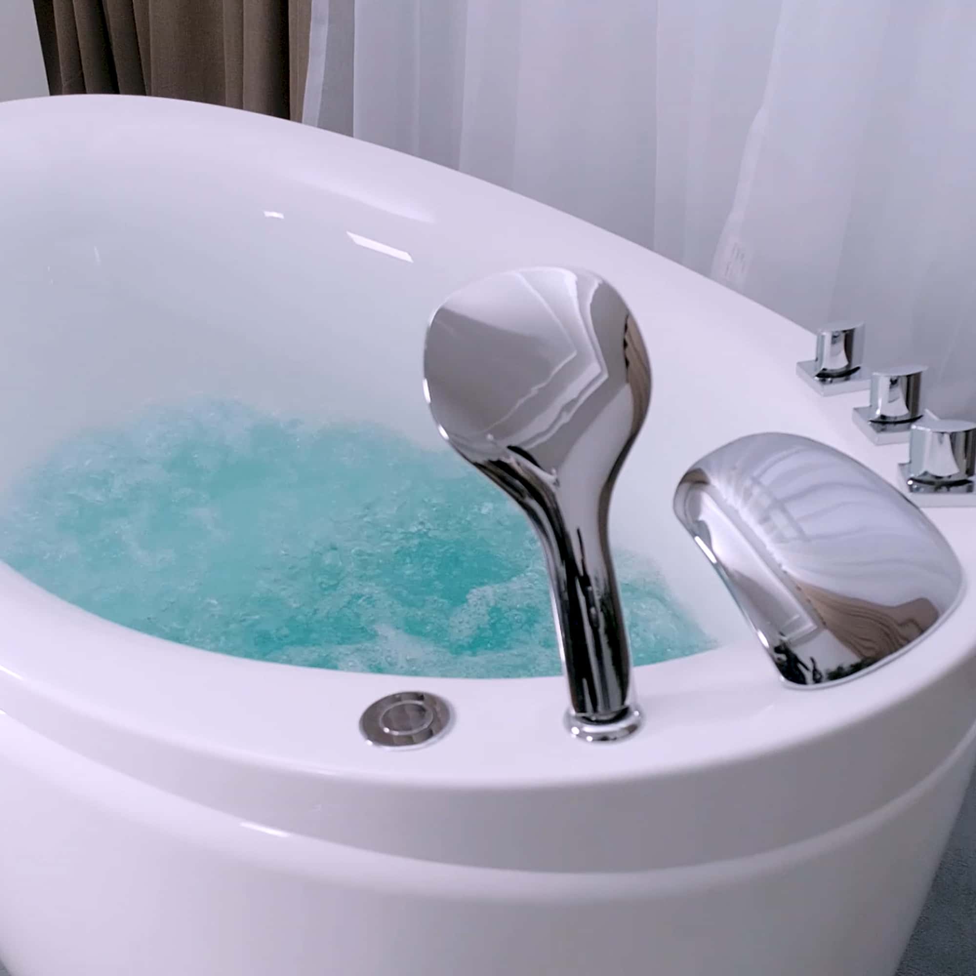 Chrome faucet and fixtures on a white freestanding air bathtub with water