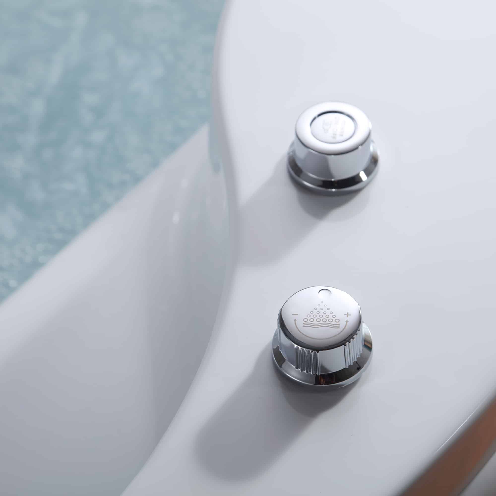 Close-up of white whirlpool bathtub controls with chrome jet buttons and dial