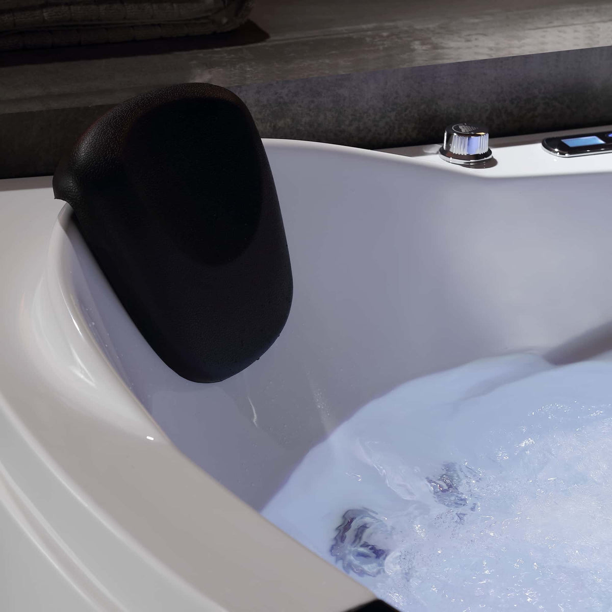 Corner whirlpool bathtub corner with black headrest and bubbling water
