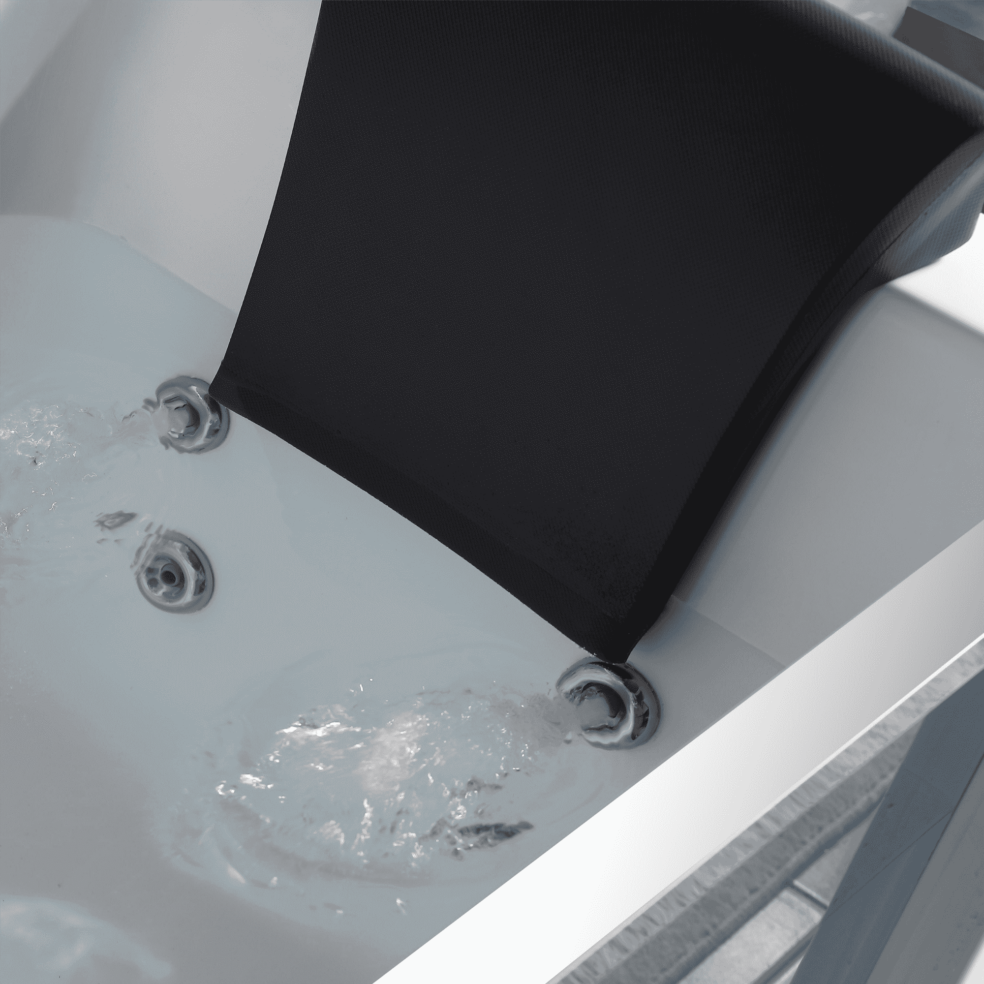 Close-up of whirlpool jets with a black headrest resting at the tub corner
