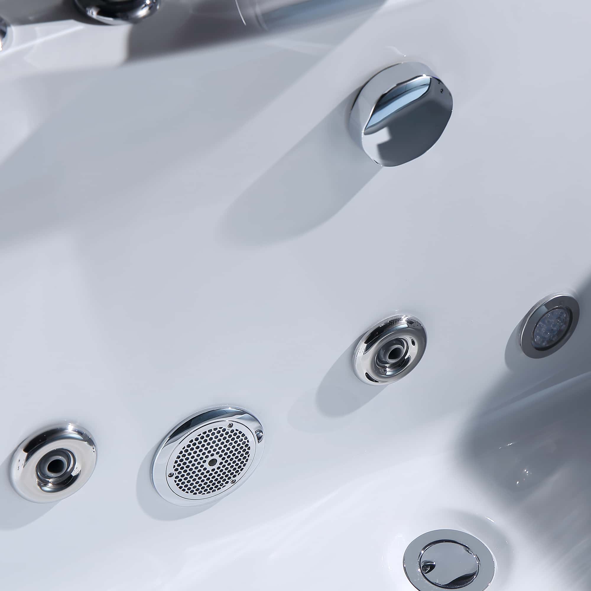 Close-up of whirlpool jet nozzles and chrome controls on a white tub