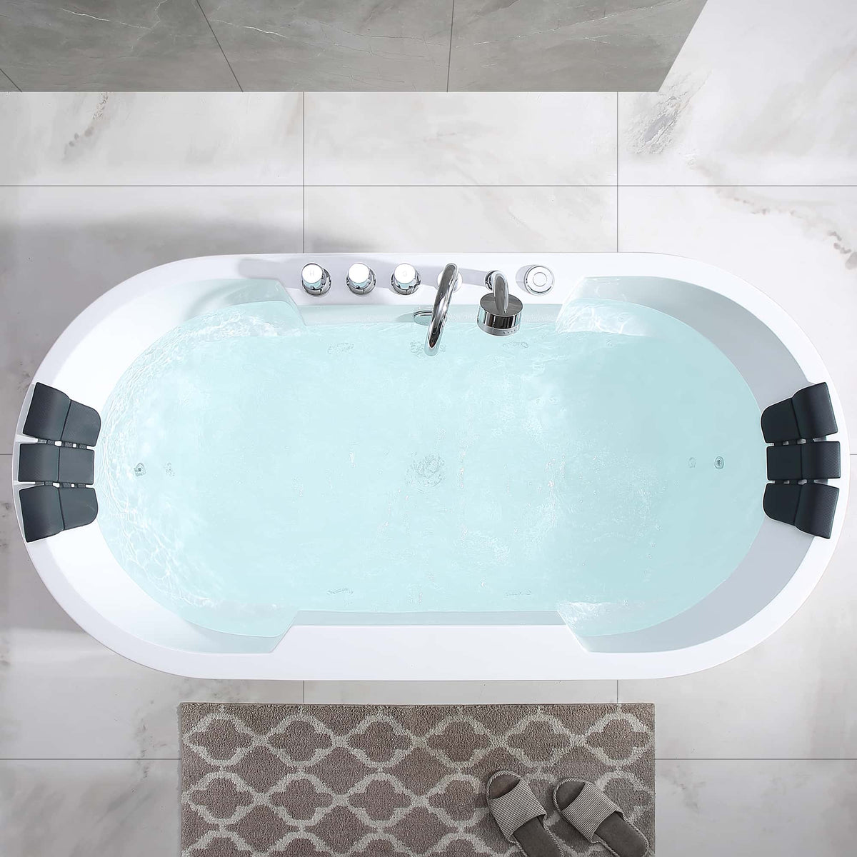 Top view of white oval whirlpool bathtub with jets, chrome controls, and filled water