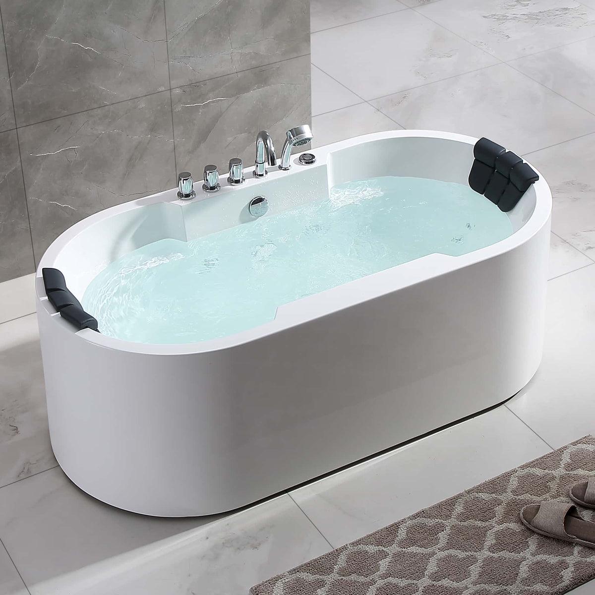 White freestanding oval whirlpool bathtub with light blue water and chrome faucet