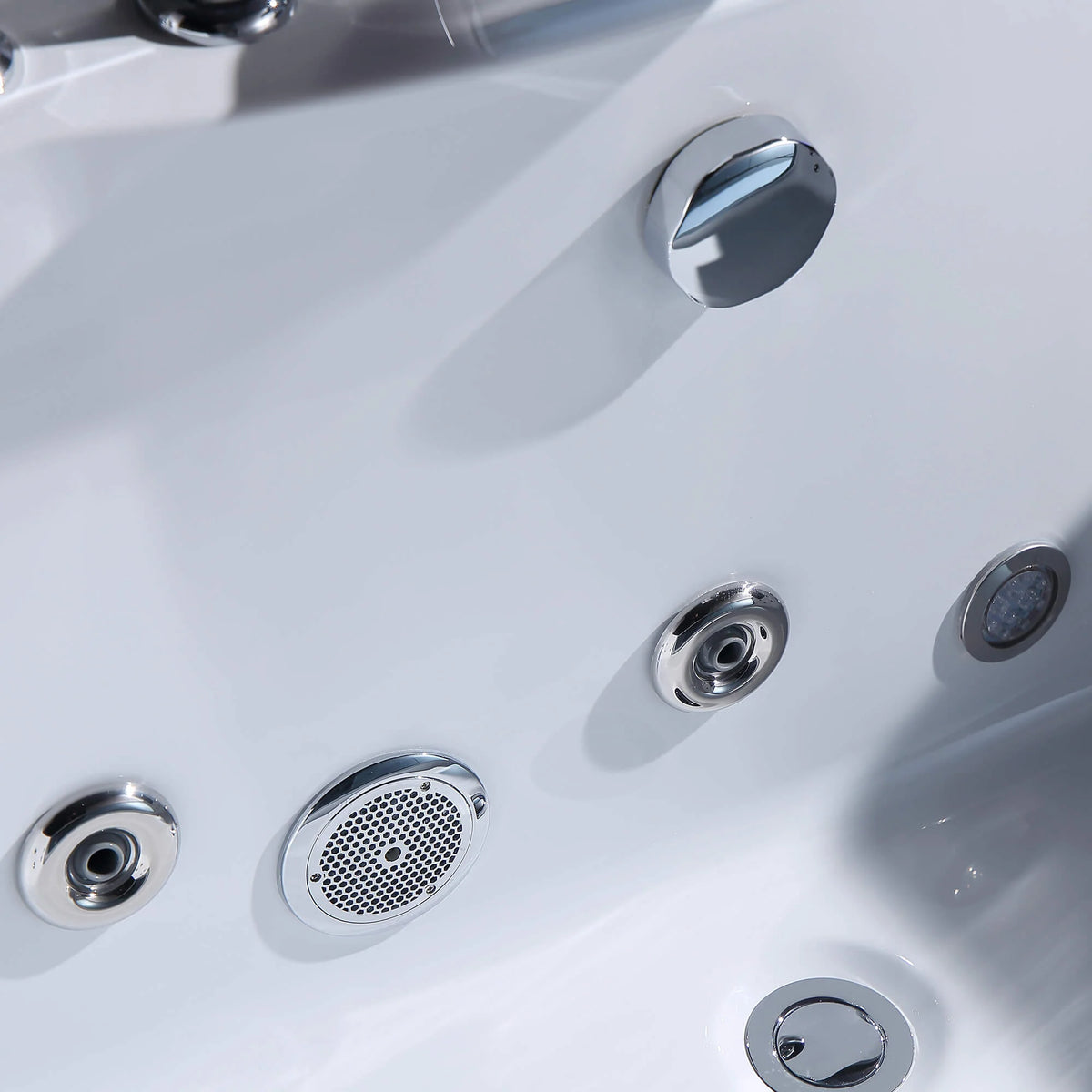 Close-up of whirlpool bathtub jets, air knobs, and drain cover on white tub
